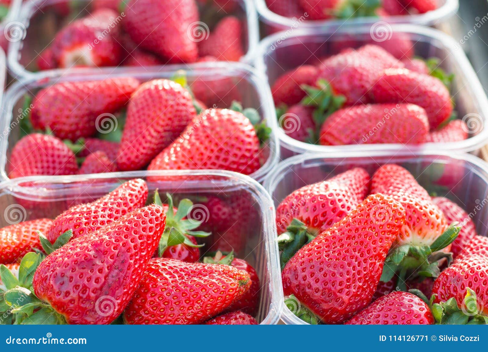 Fresh Strawberries in Plastic Boxes or Baskets at Marketplace. Stock