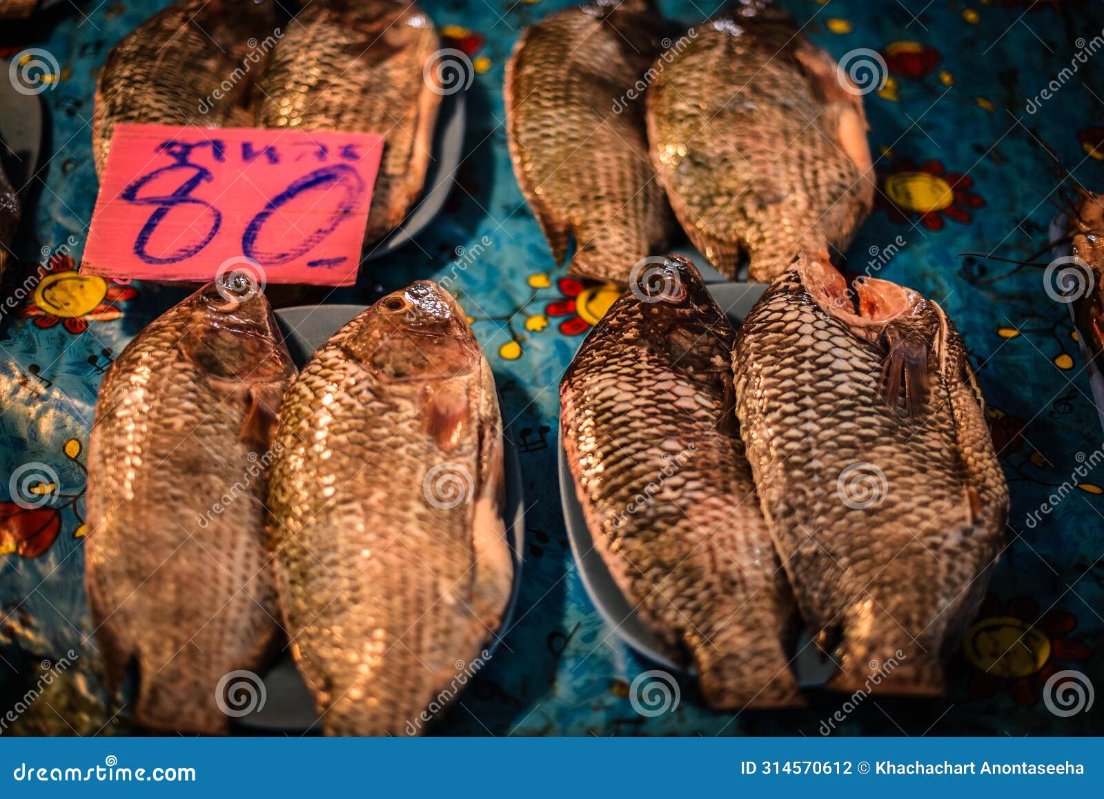 fresh tilapia are scaled, gutted and put on a plate for sale at a fresh market