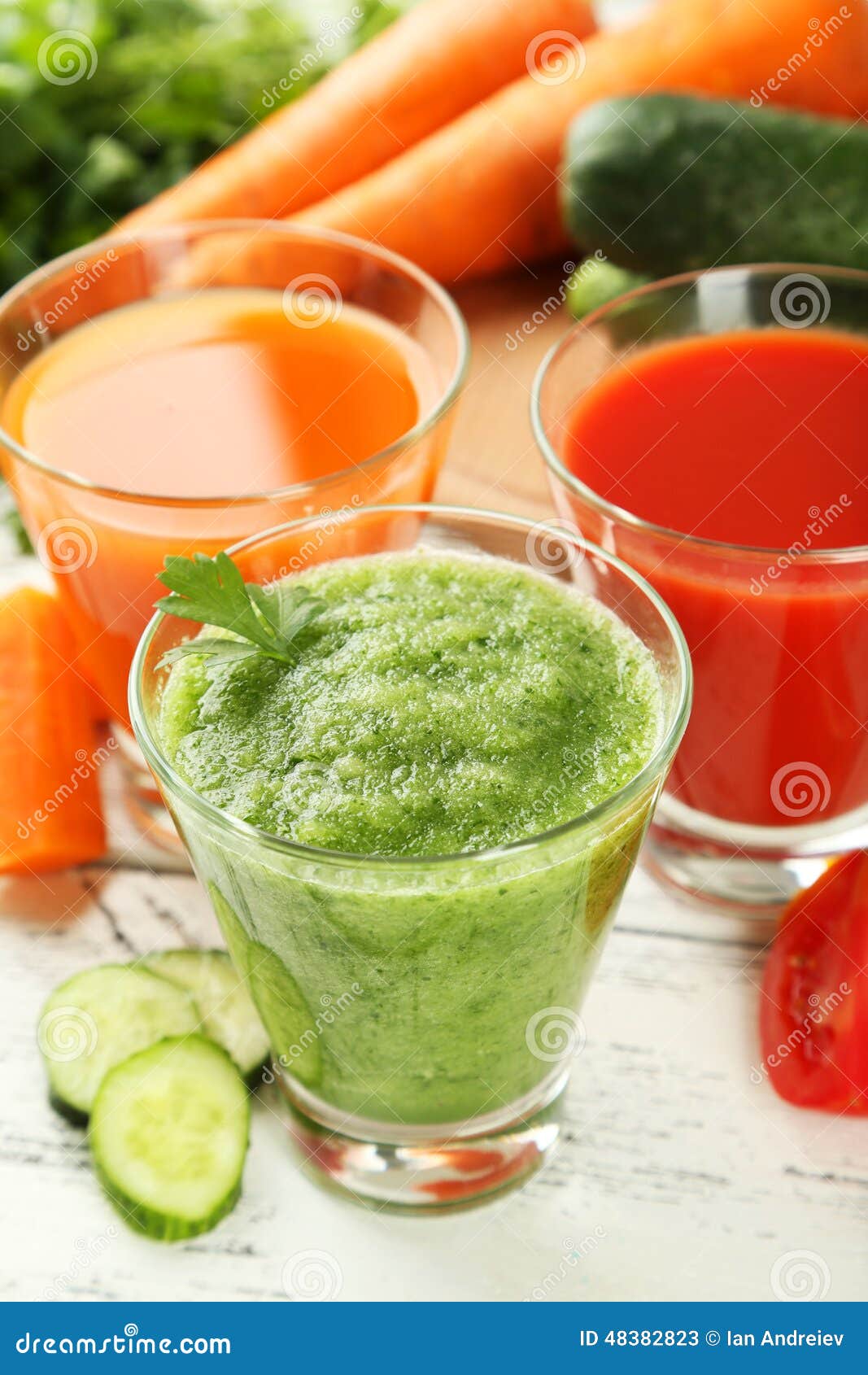 Fresh tomato, carrot and cucumber juice on white wooden background