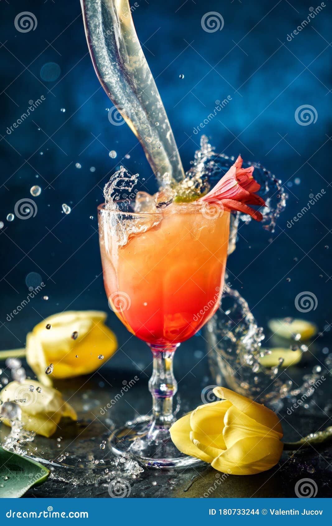 Fresh Tropical Cocktail with Ice and Flowers in Wineglass on Dark Blue Background photo image