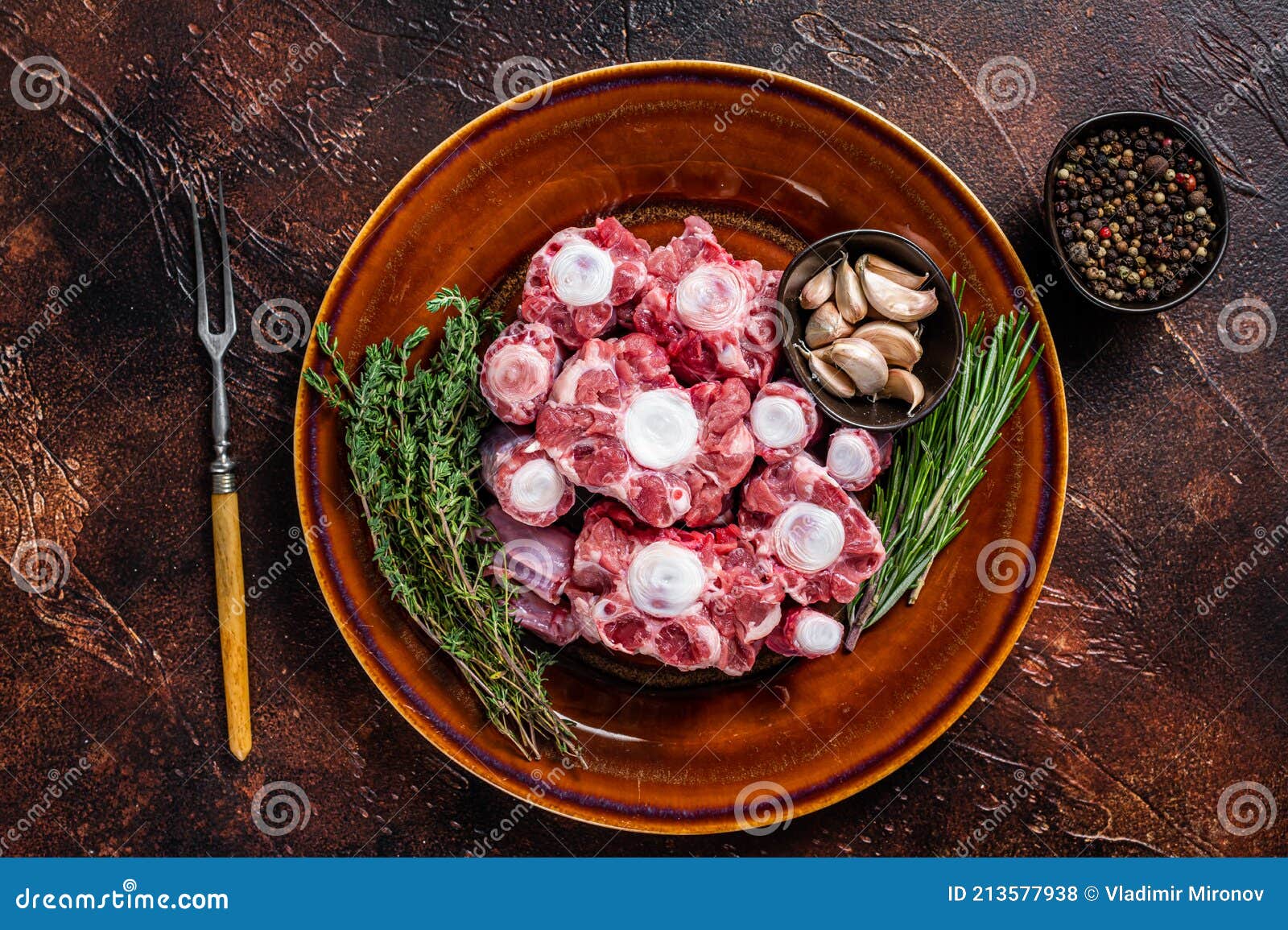 Fresh Uncooked Beef Oxtail Cut Meat on Rustic Plate with Herbs. Dark