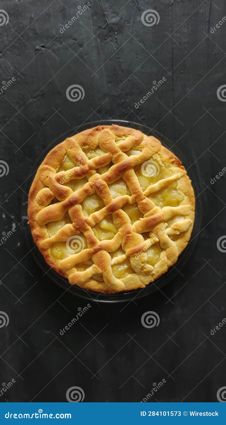 freshly-baked, golden-brown pie sits atop a black plate on a black table