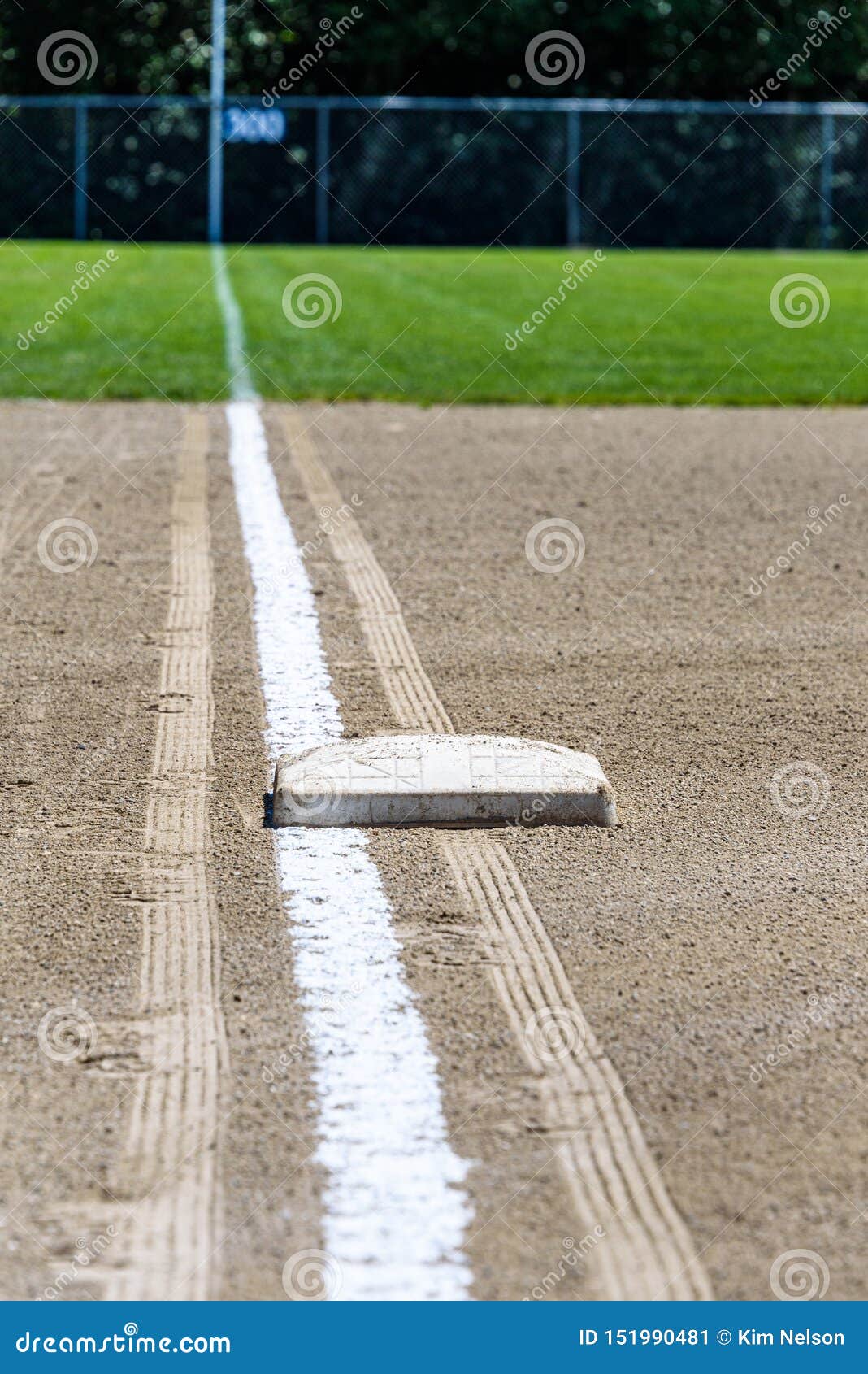 freshly chalked baseline, with third base plate, running out to the 300 yards sign, empty baseball field on a sunny day