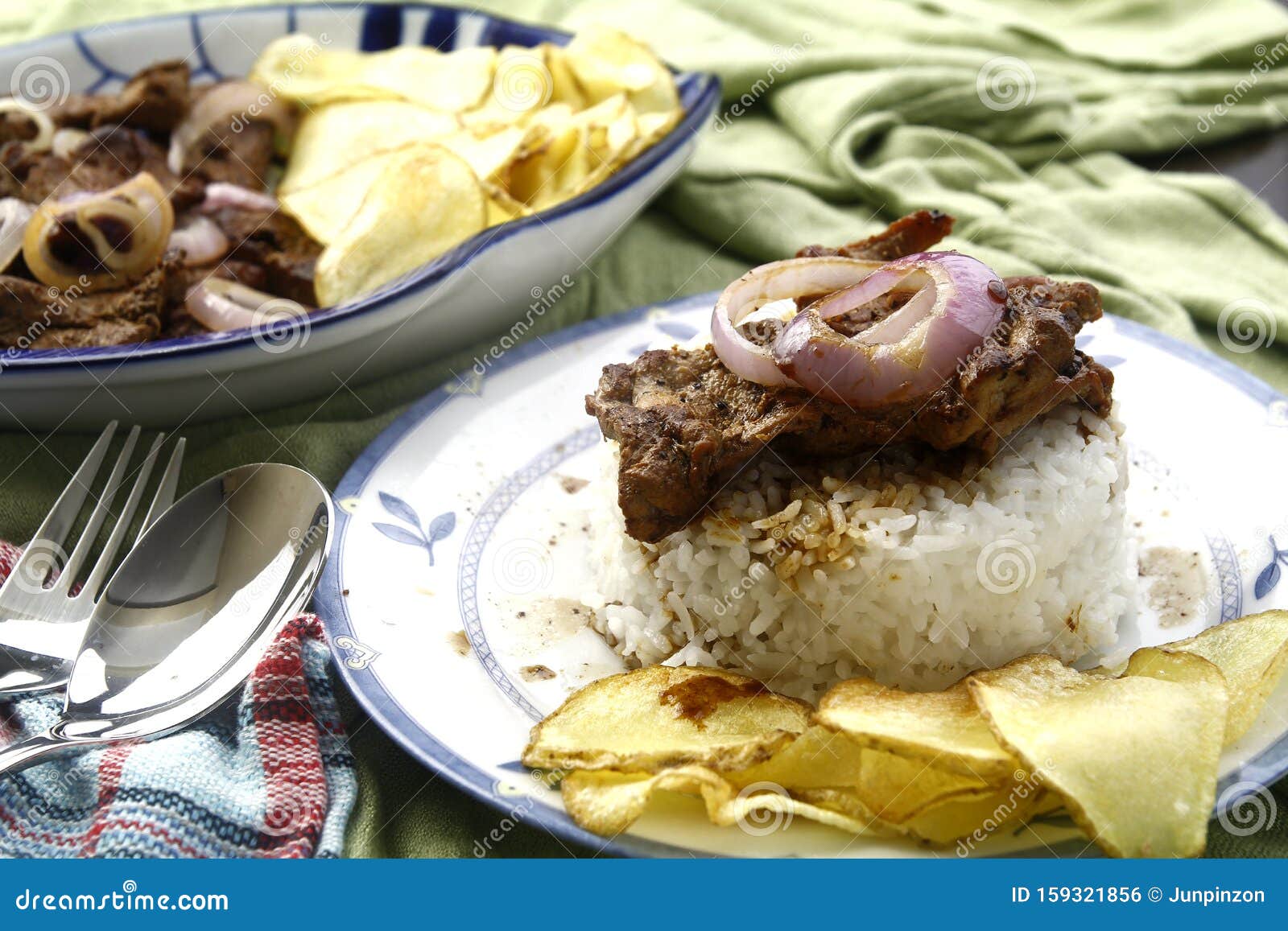 bistek tagalog or fried pork tenderloin in soy sauce with potato chips