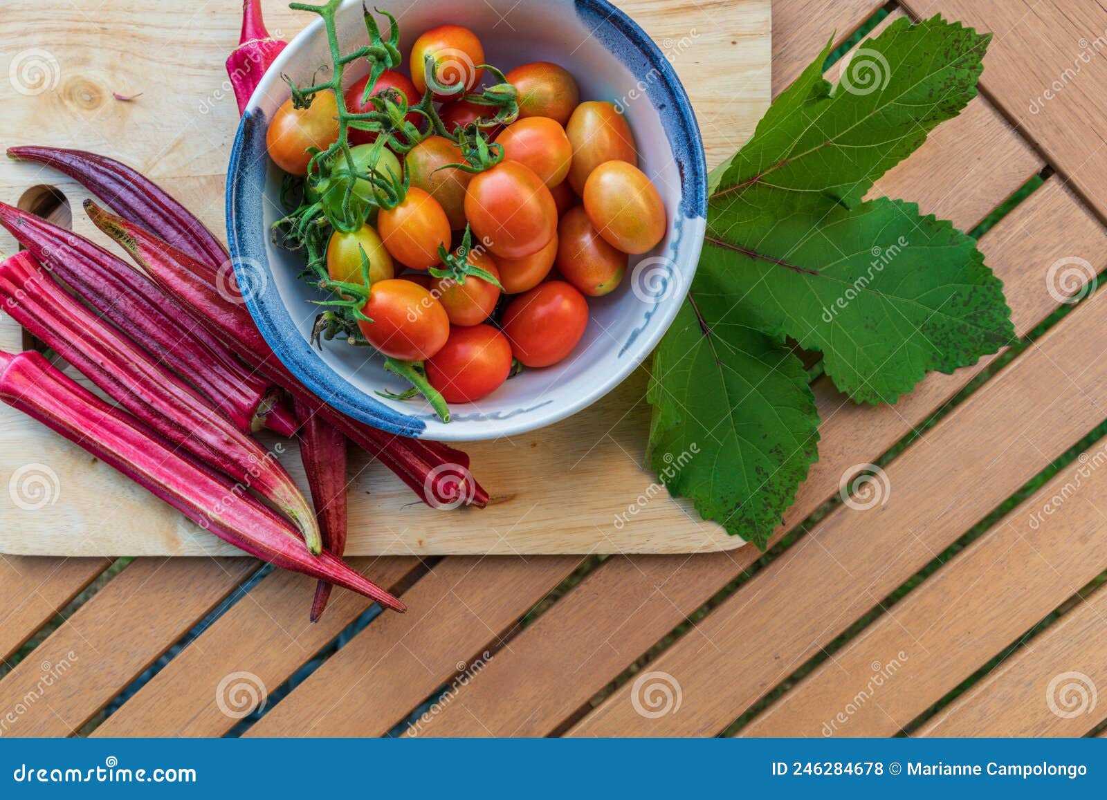 fresh picked grape tomatoes and okra with an okra leaf