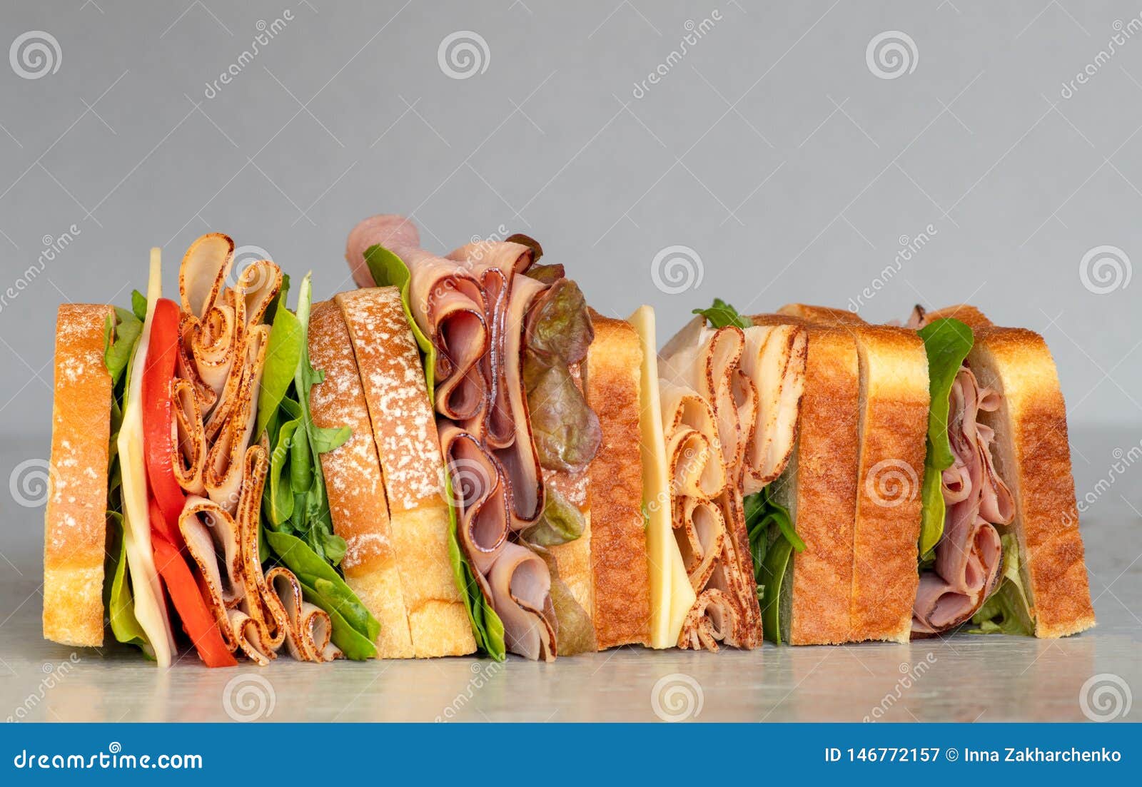 freshly made deli style sandwich with lettuce, several different kinds of vegetables, tomatoes, cheese, meats similar to ham,