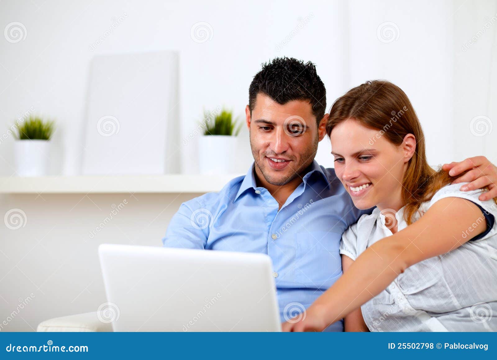 Freundliche junge Paare unter Verwendung des Laptops zusammen