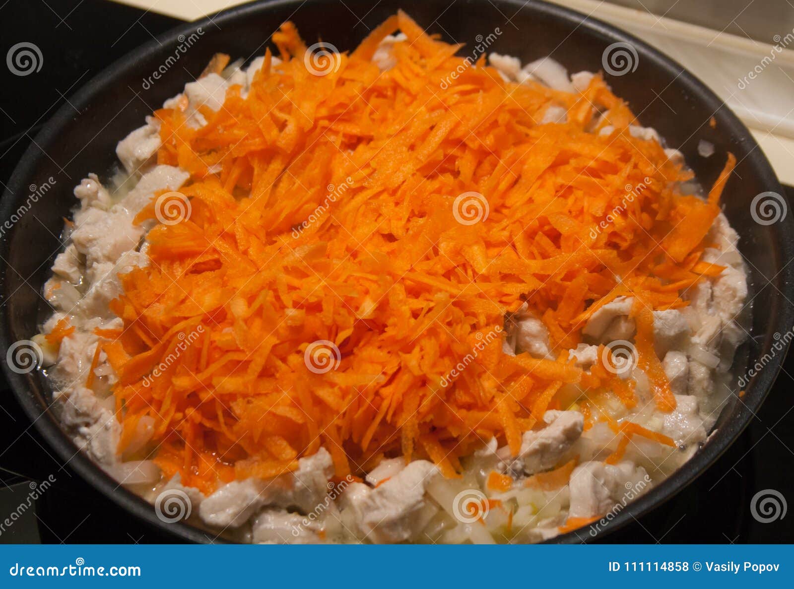 Fried Chicken with Onions and Carrots in a Frying Pan Stock Photo