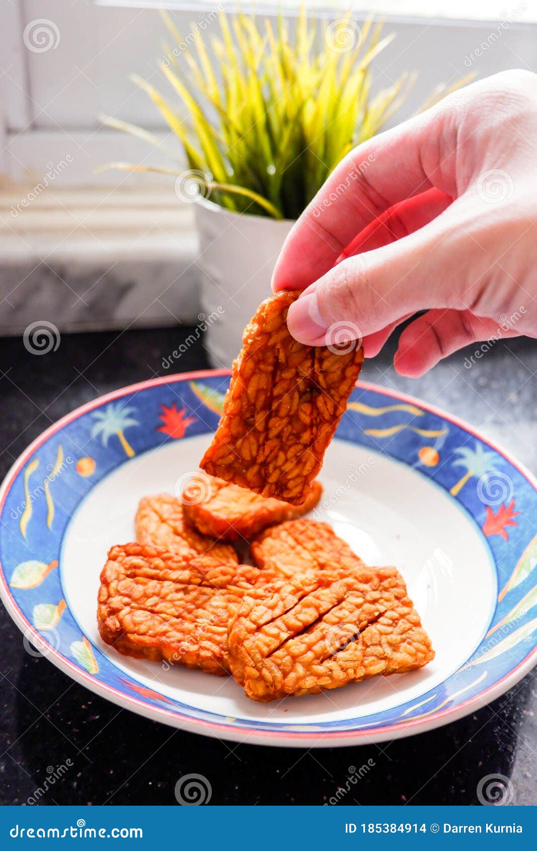 fried tempeh / tempe held by hand, indonesians usually eat these savory snacks using their hand. tempeh a traditional indonesian s