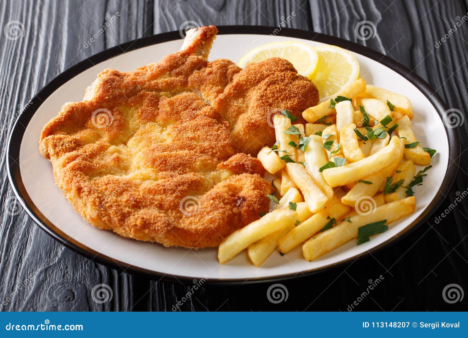 fried veal cutlet milanese with lemon and french fries close-up