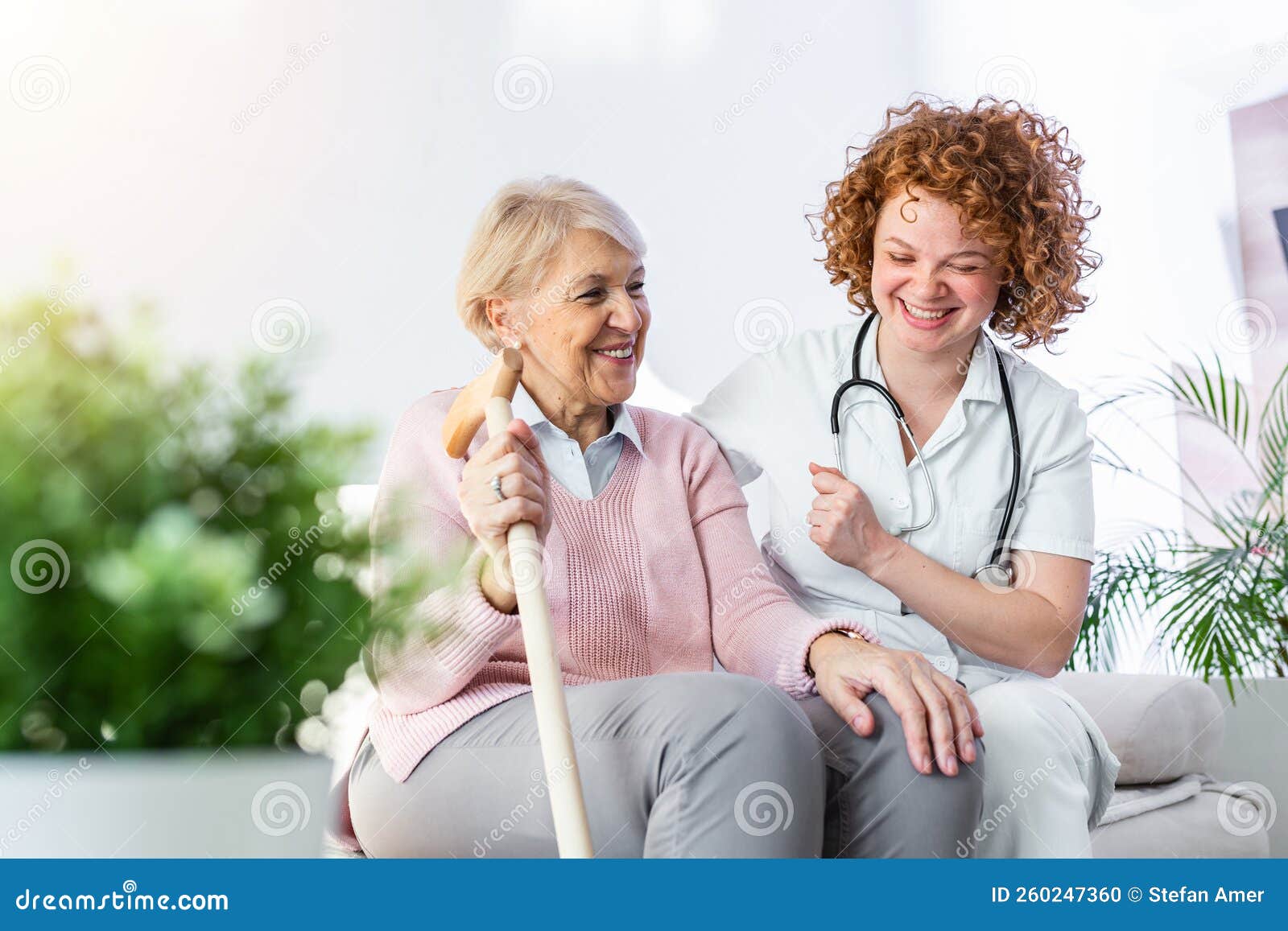 Friendly Relationship Between Smiling Caregiver In Uniform And Happy Elderly Woman Supportive
