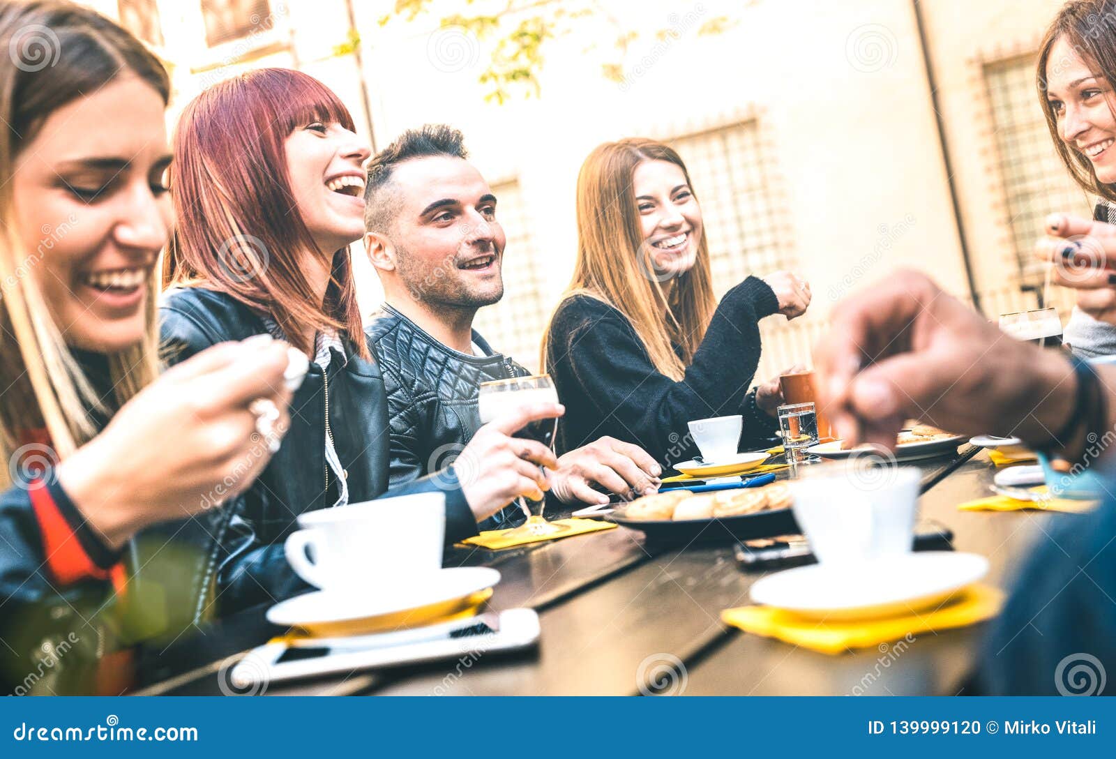 friends drinking cappuccino at coffee restaurant - millenial people talking and having fun together at fashion bar cafeteria