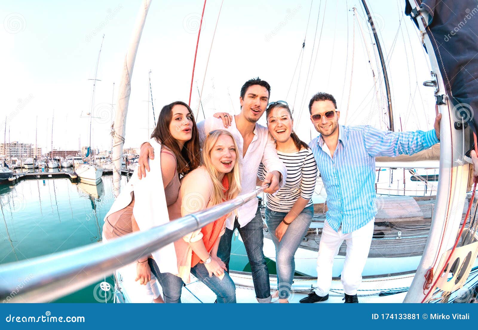 friends group taking selfie pic with stick on luxury sailing boat party trip - friendship concept with young millenial people