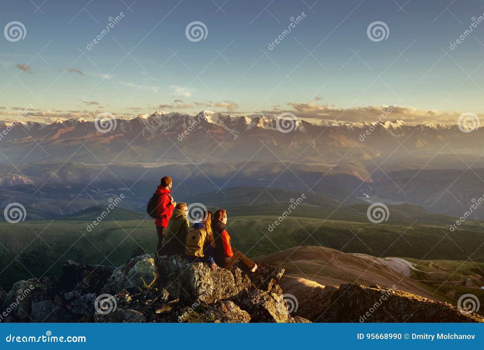 Four friends on mountain top looking to sunset