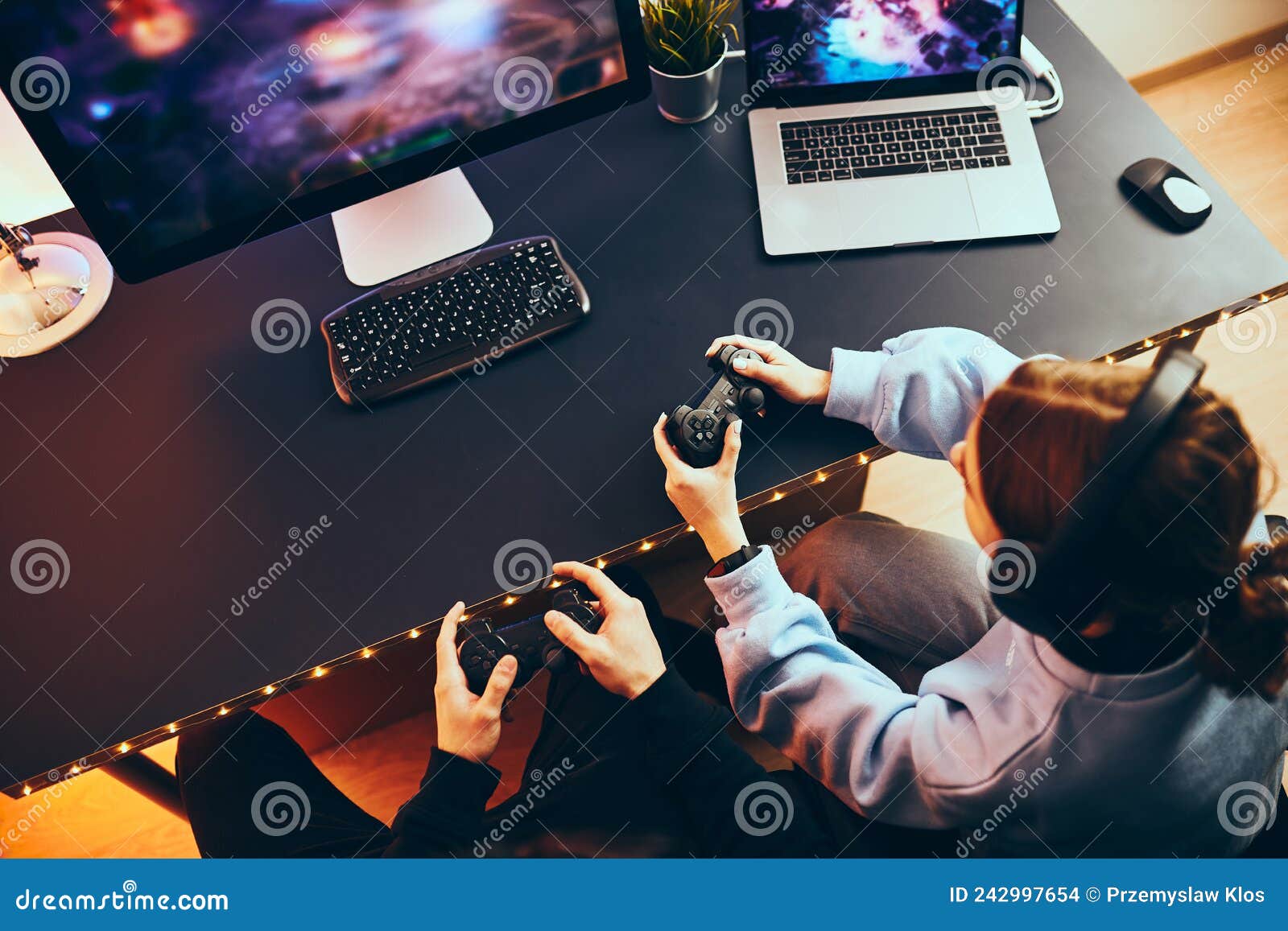 Friends playing video game at home. Gamers playing online in dark room lit  by neon lights. Competition and having fun - a Royalty Free Stock Photo  from Photocase