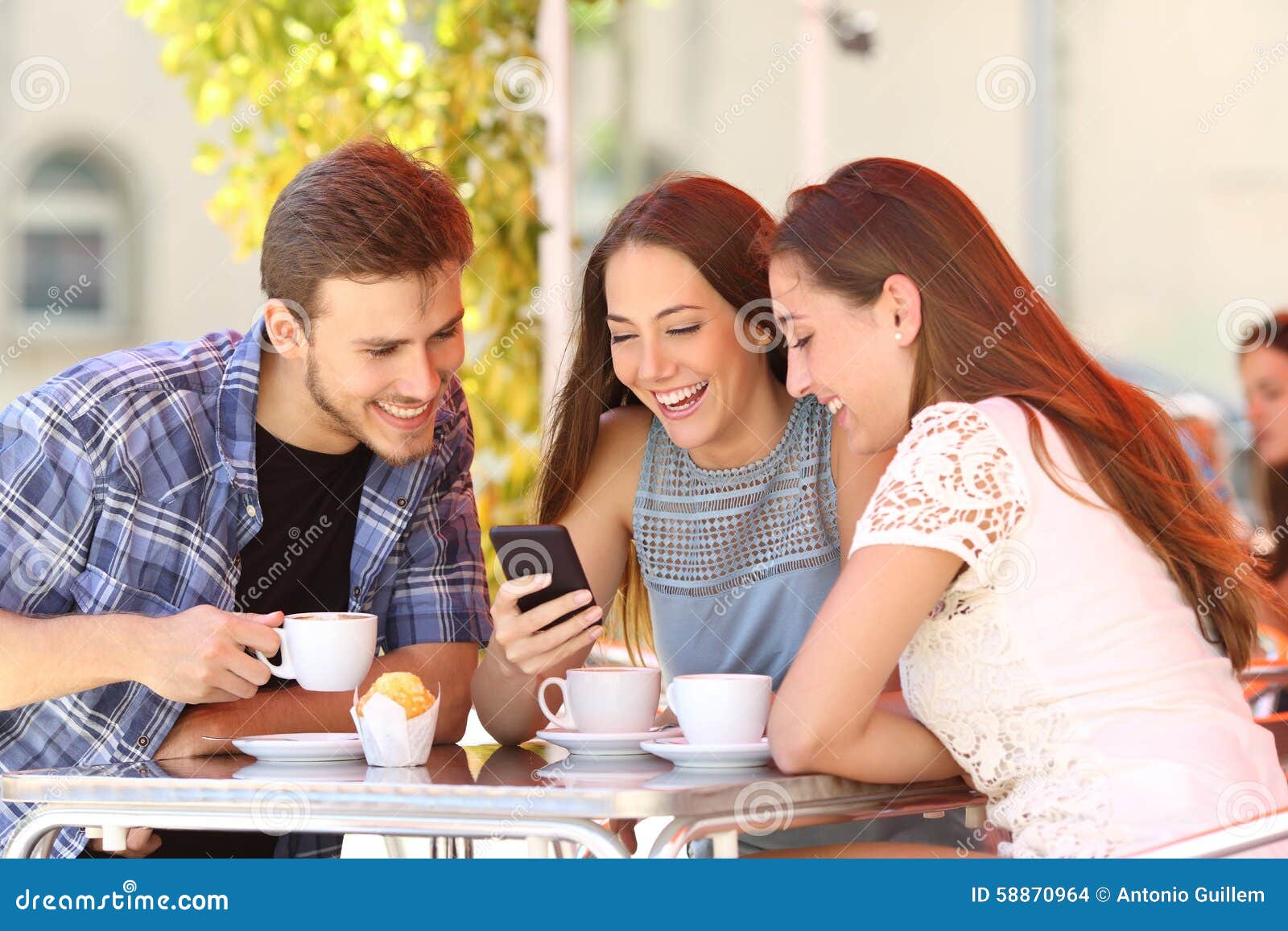 friends watching media in a smart phone in a coffee shop