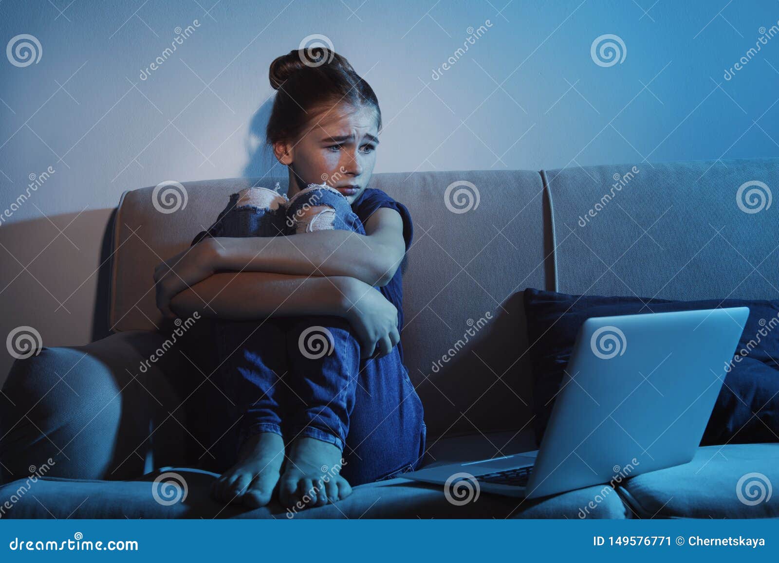 frightened teenage girl with laptop on sofa. danger of internet