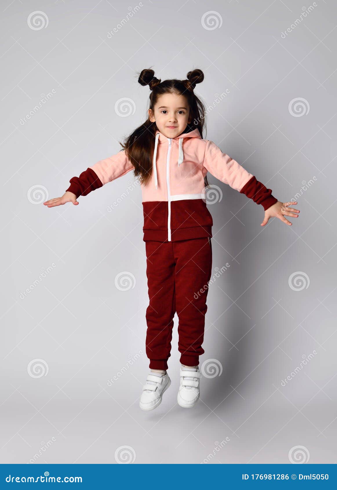frolic brunette kid girl in modern fashion pink brown sportwear is jumping having fun