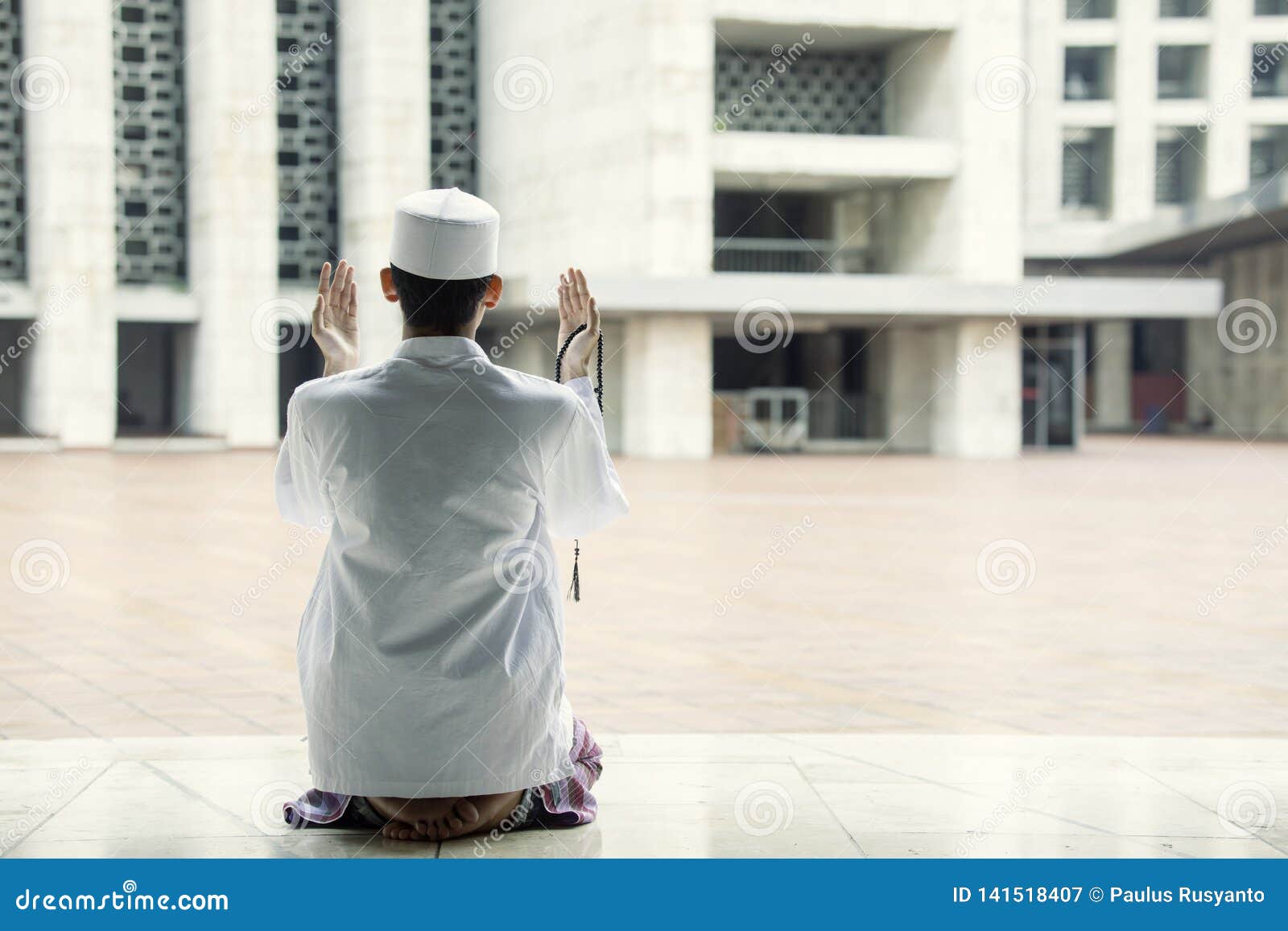 Frommer Mann betet zum Allah in der Moschee. Hintere Ansicht eines frommen Mannes, der zum Allah beim Sitzen in der Moschee betet