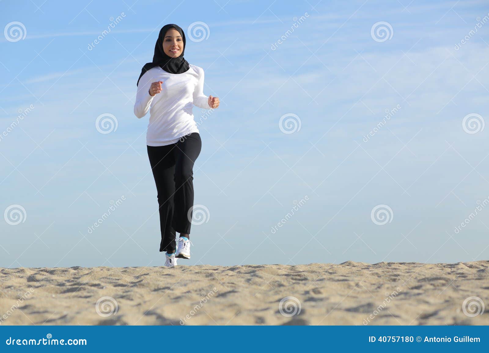 front view of an arab saudi emirates woman running on the beach