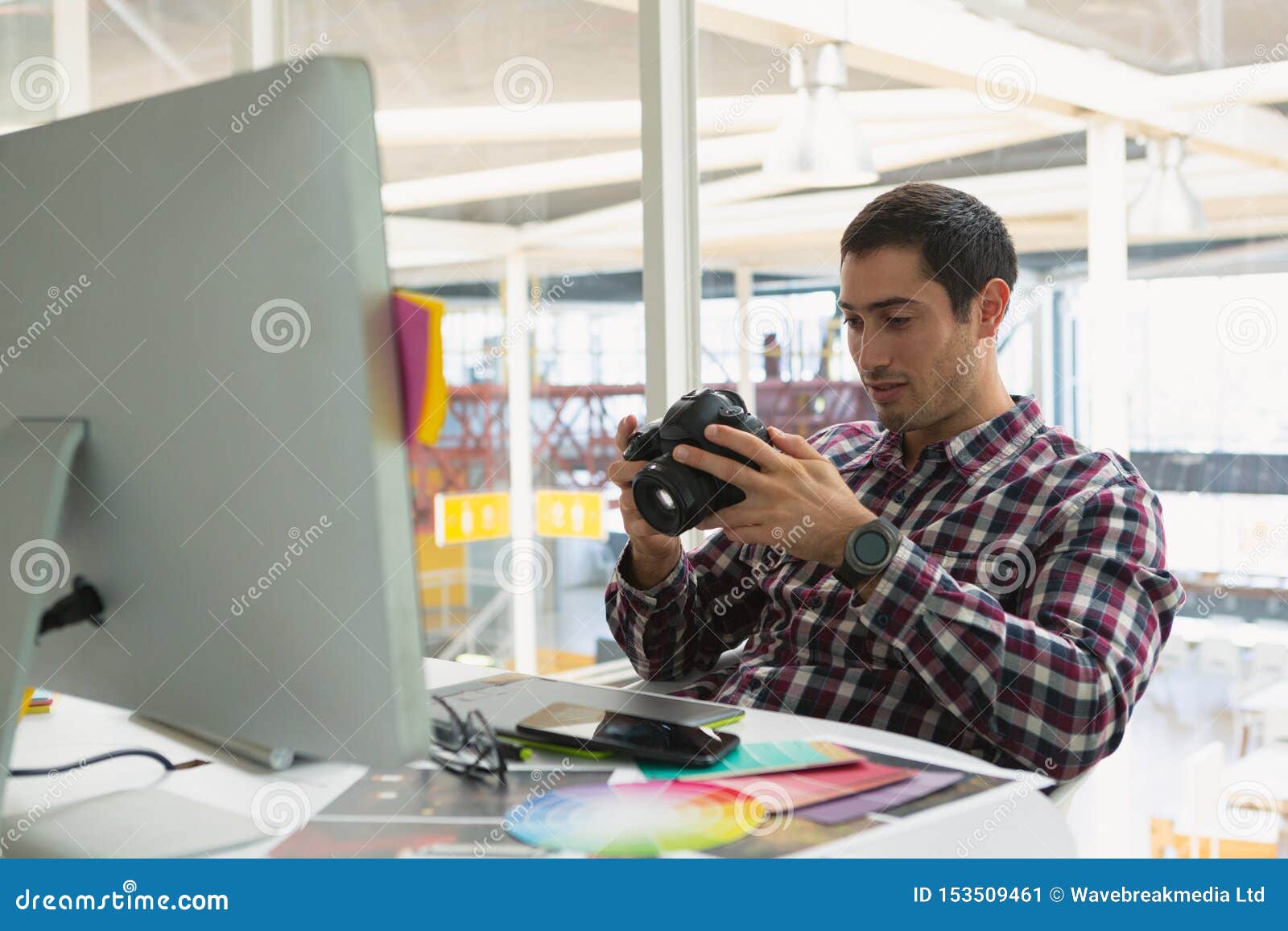 male graphic er using digital camera on desk
