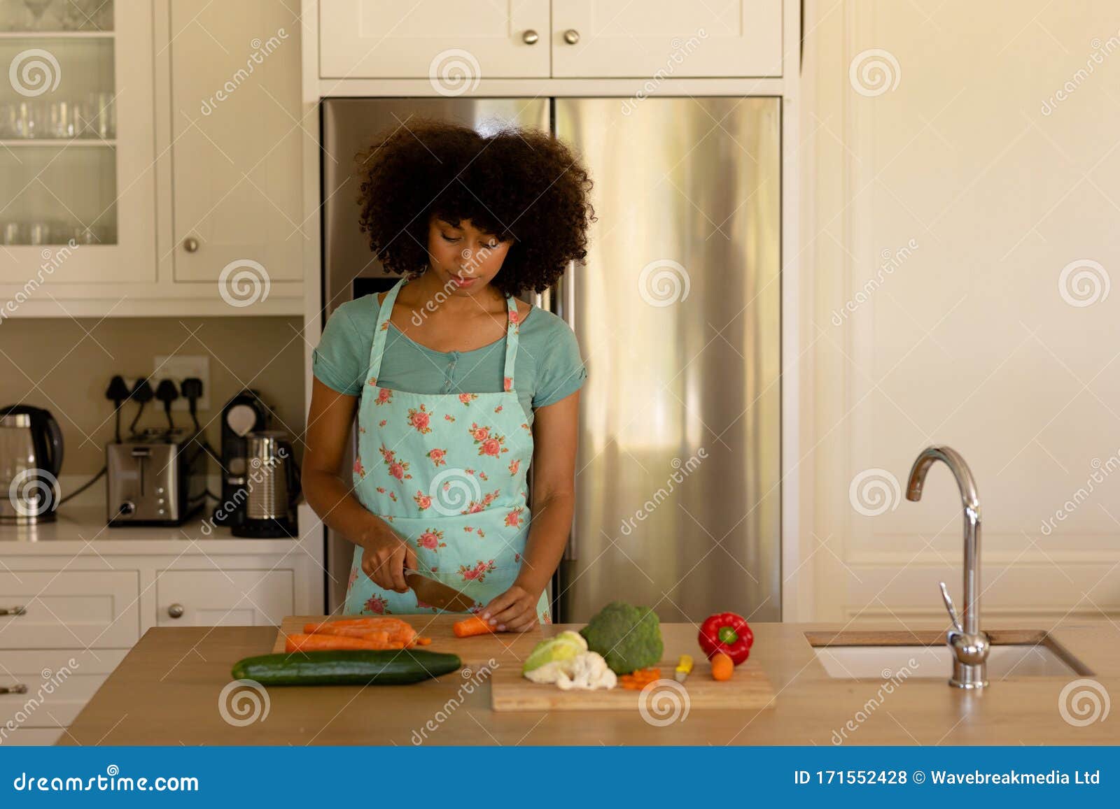 Young Woman Standing In Her Kitchen Wearing Apron Cooking 