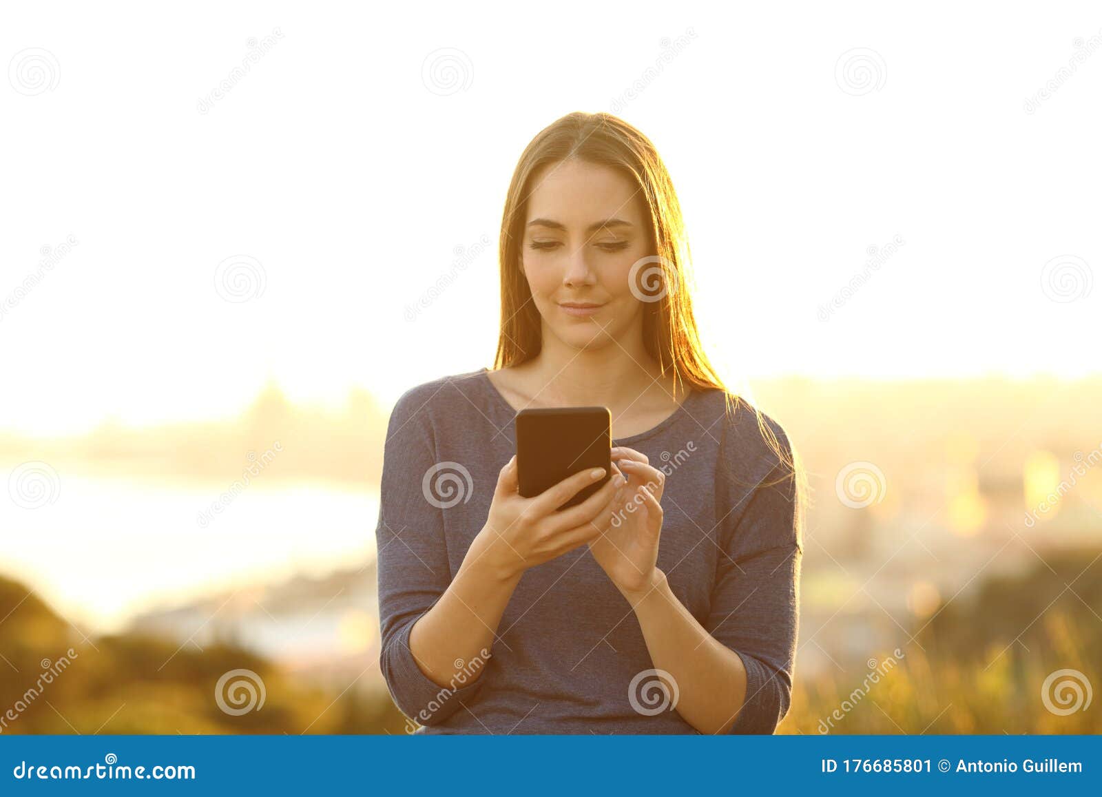 woman using smart phone on the outskirts at sunset