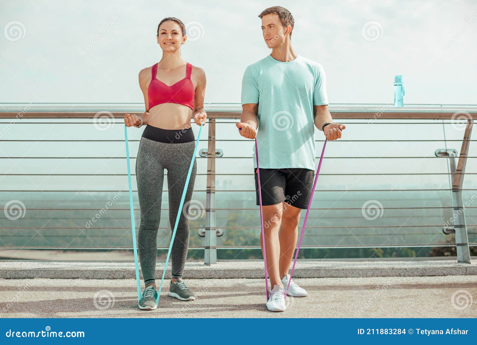 Front View of Two Athletes Exercising with Rubber Bands Outdoors in the