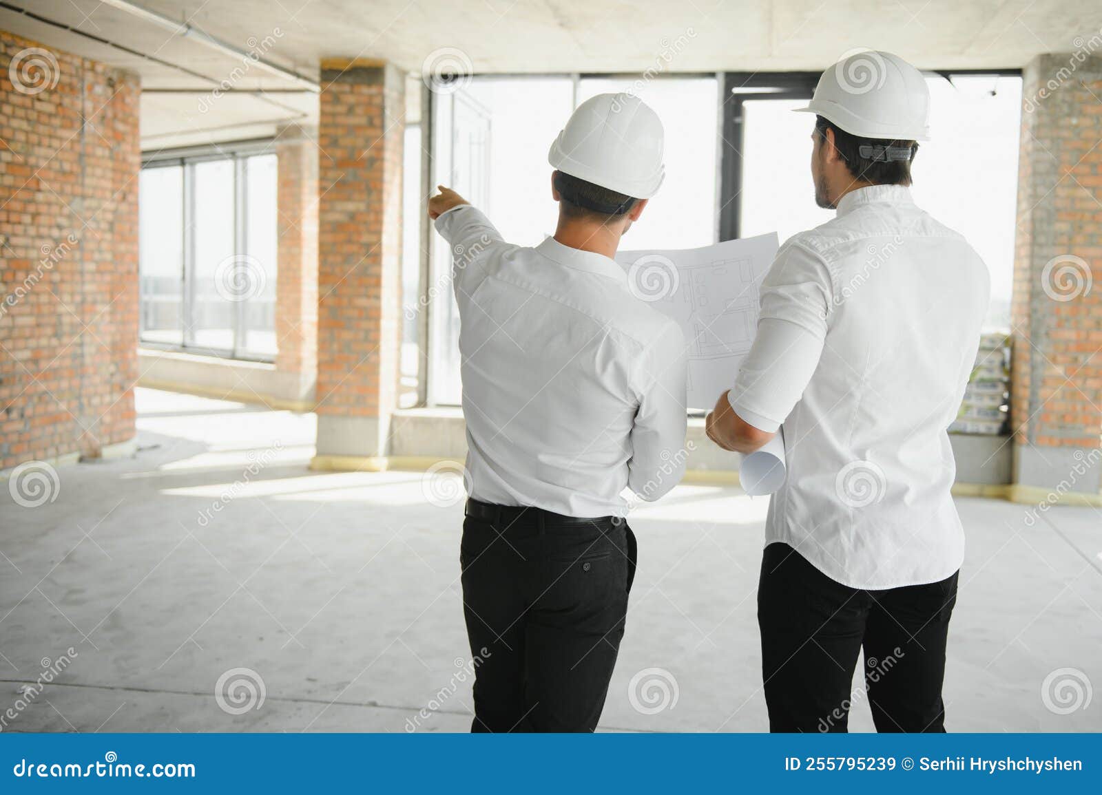 A Front View of Two Smart Architects with White Helmets Reviewing