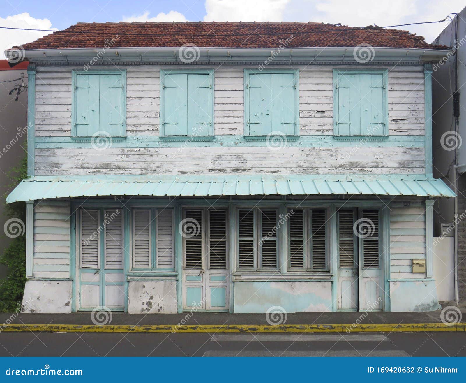 front view of a typical wooden and rusted house in martinique, french west indies. tropical blue and white windows