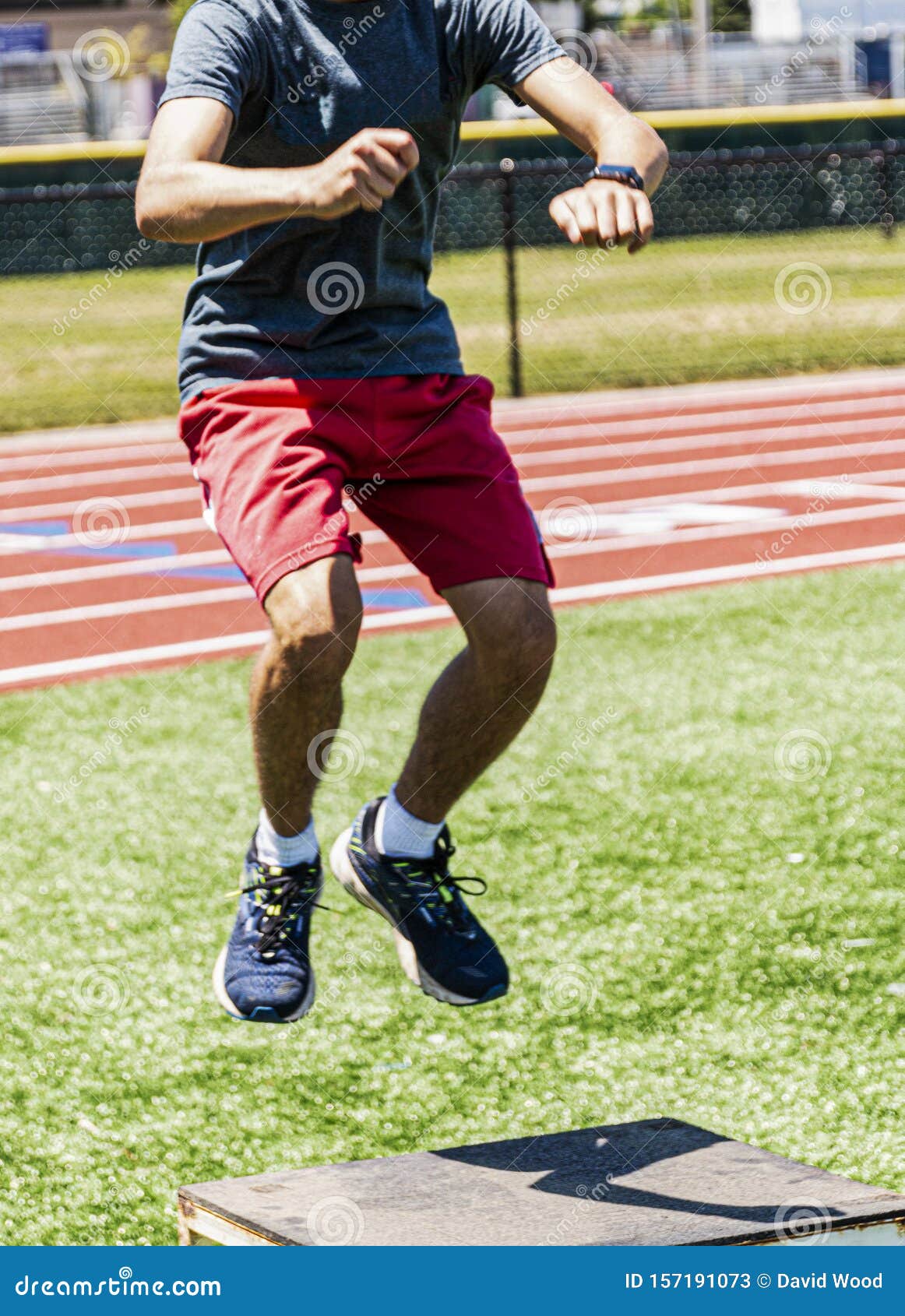 Young Athlete Doing Box Jumps on a Turf Field with Track in Background