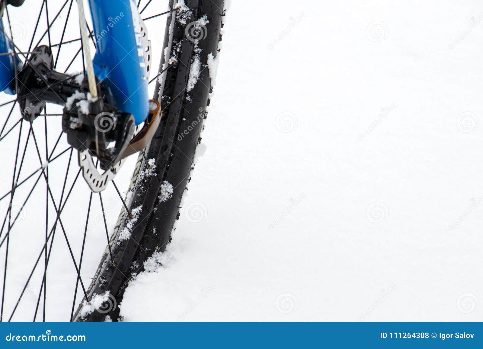 Frontowi koła rower górski zostają w śniegu i podążają ścieżkę Śnieżni płatki unosi się na ciemnych dróg oponach. Frontowy koło roweru górskiego pobyt w śniegu