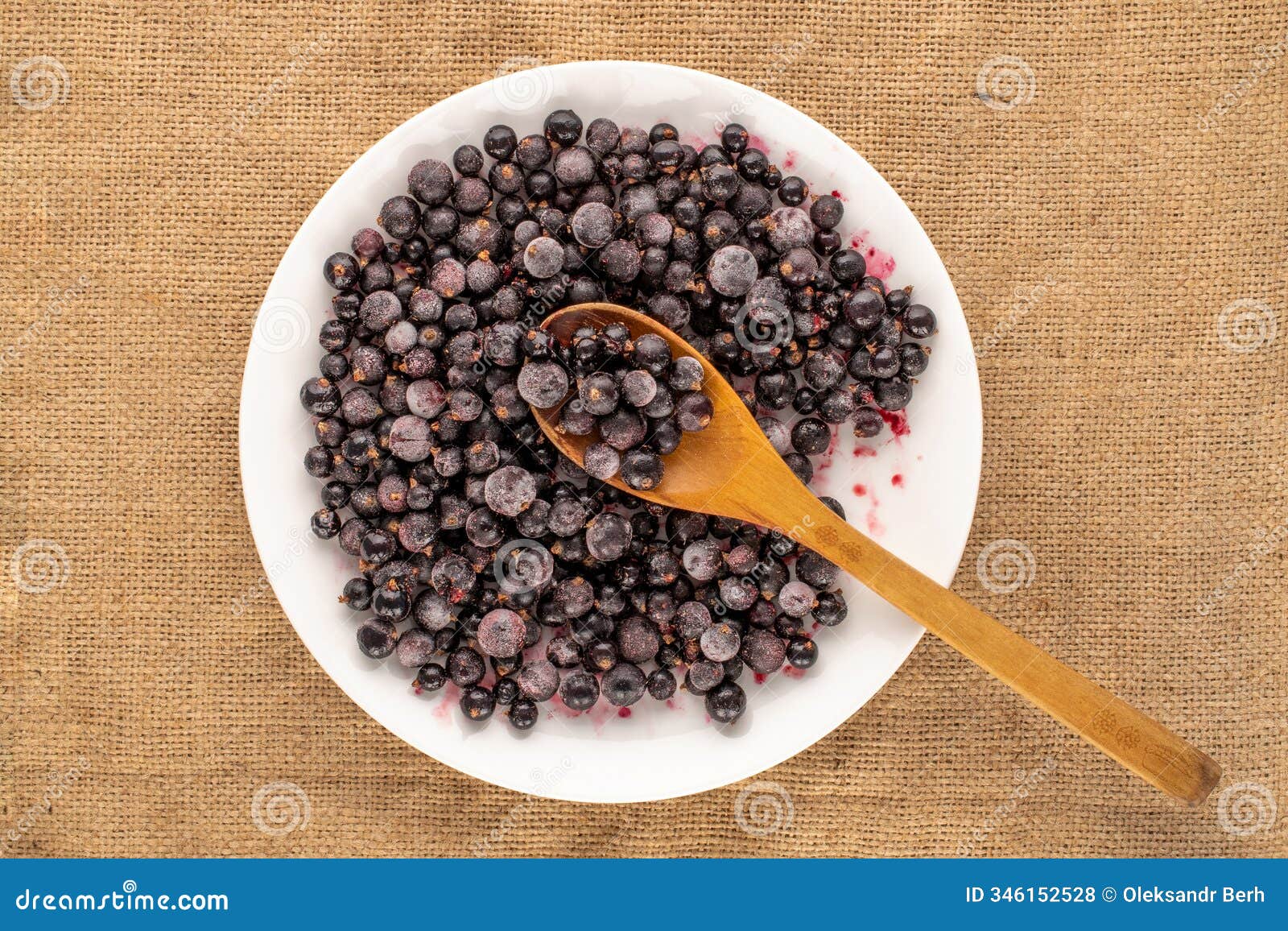 frozen blackcurrant berries on a homemade ceramic dish, macro,  on a white background and top view.