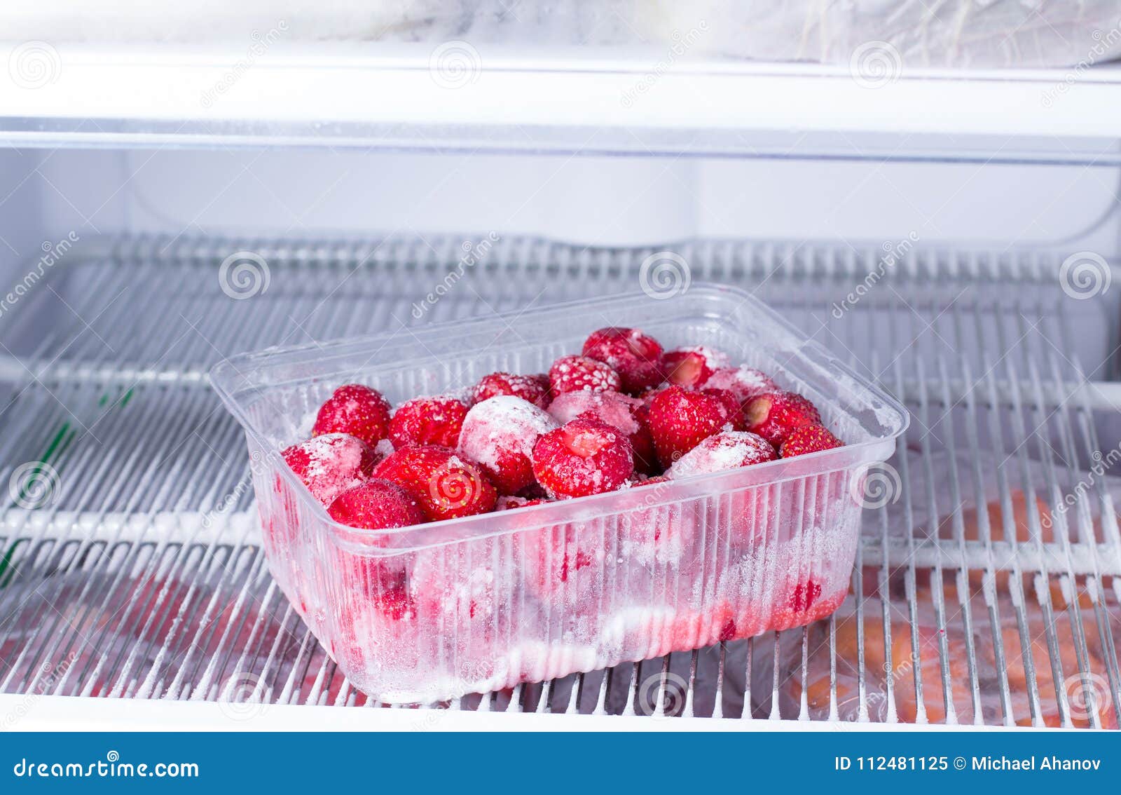 Frozen Strawberries in a Plastic Container in the Freezer Stock Image