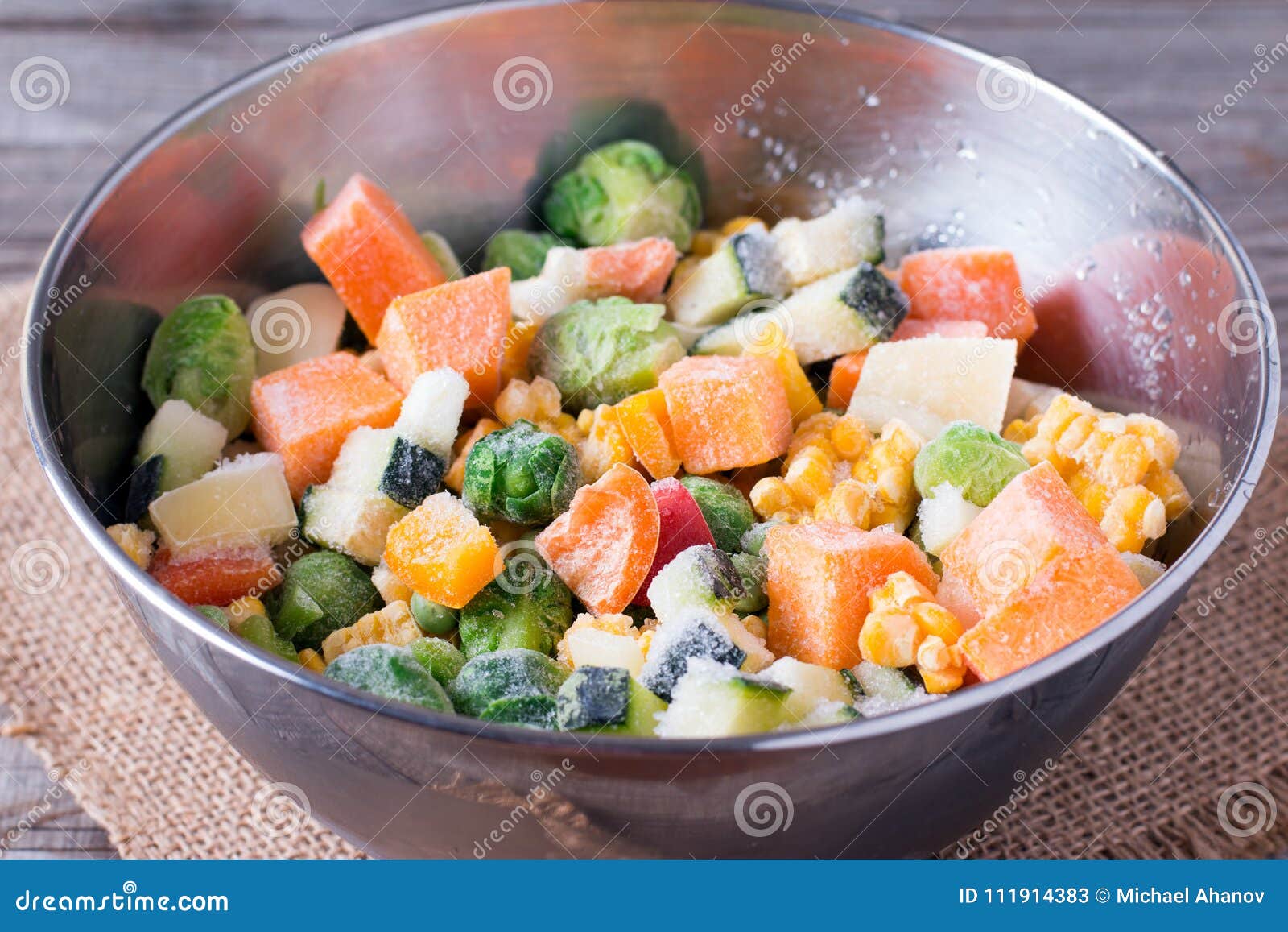 frozen vegetables in bowl on wooden table background.