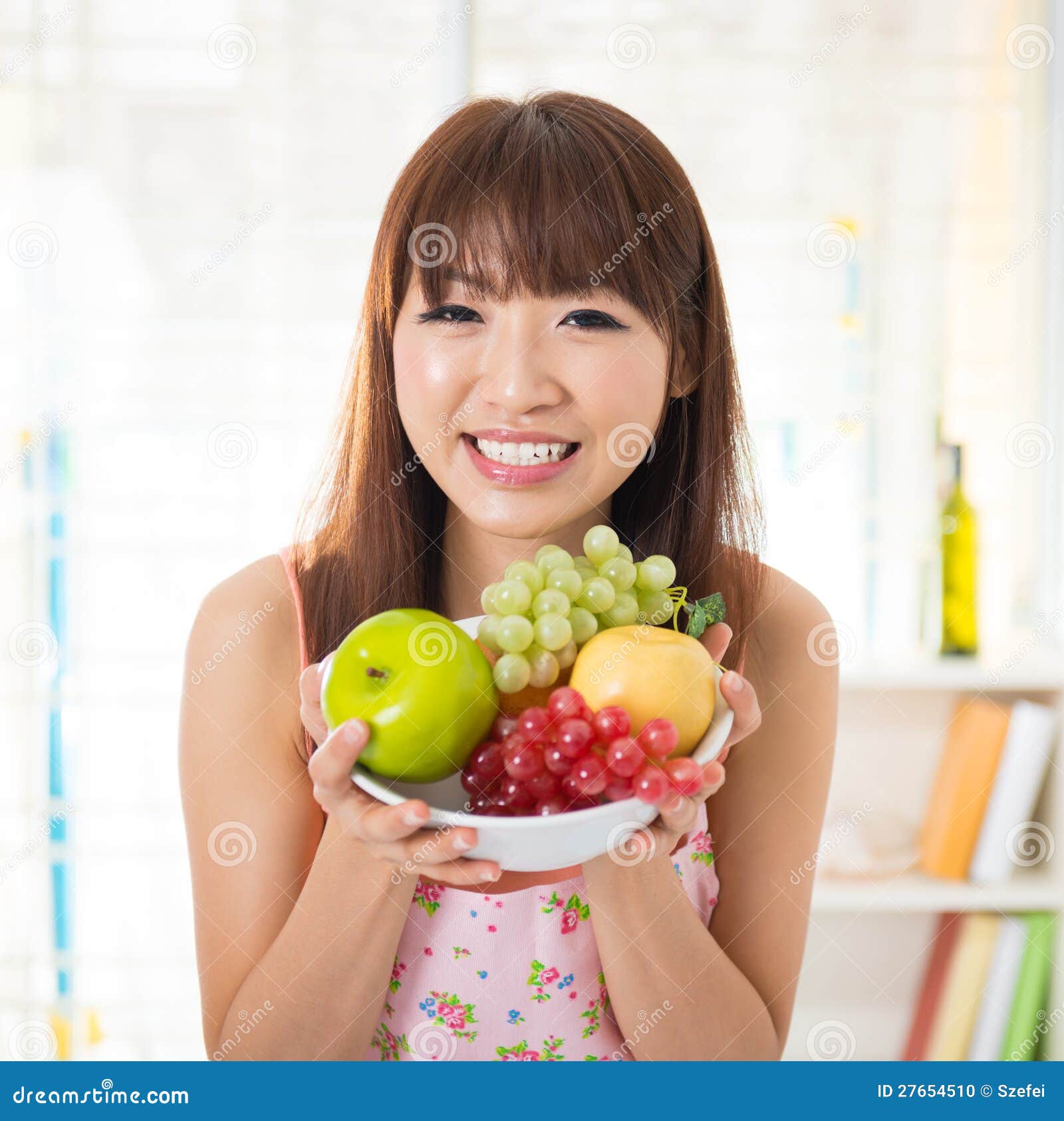 Femme asiatique retenant un fruit frais de cuvette