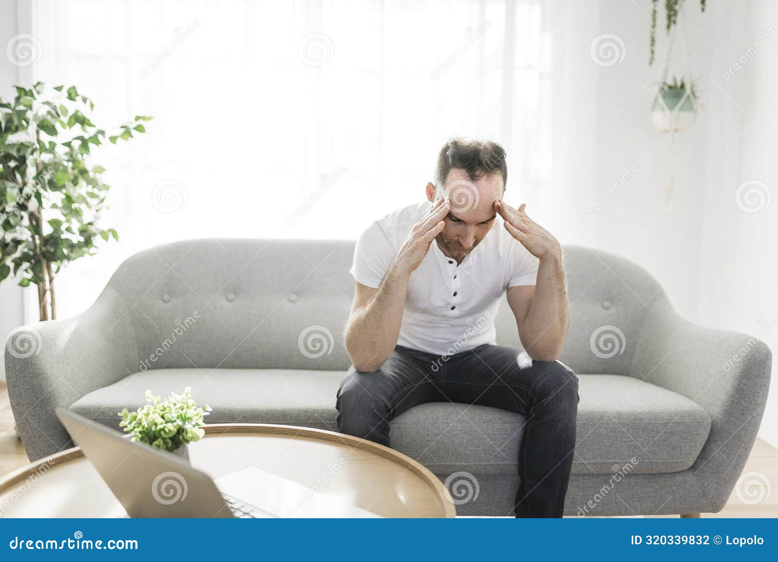 Frustrated Handsome Man with Problem Sitting on the Couch at Home Stock