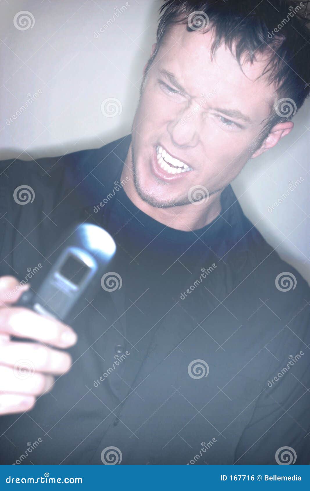 Frustrierter Mobiltelefon-Benutzer. Junger Mann verzieht in der Frustration an seinem Mobiltelefon Gesicht. Weicher Fokuseffekt angewendet.