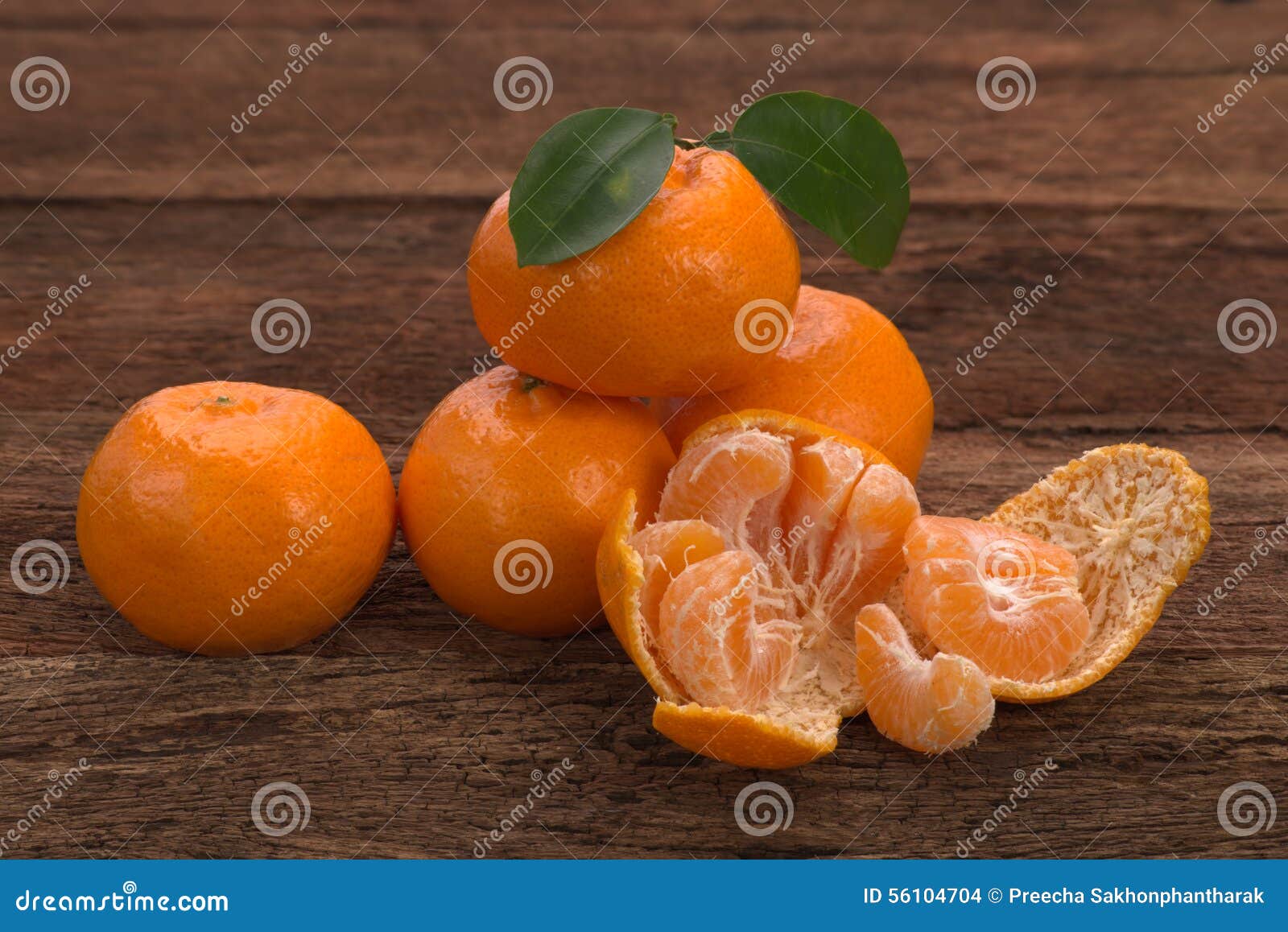 Fruta madura del mandarín con las hojas y un abierto pelada. La fruta madura del mandarín con verde se va y un lugar abierto pelado en la madera rústica vieja de la mirada