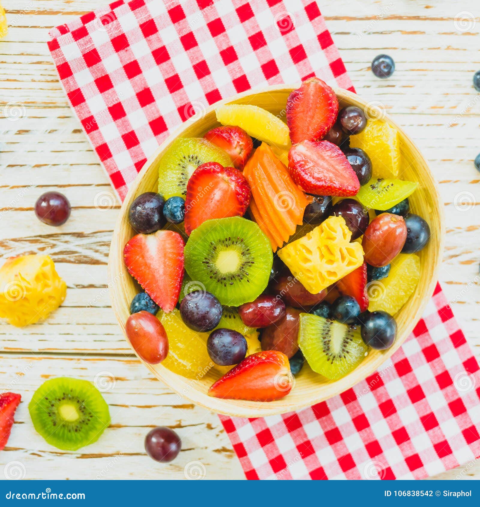 Frutti misti e assortiti con l'uva della fragola del kiwi ed altro in ciotola sulla tavola di legno - filtri l'elaborazione