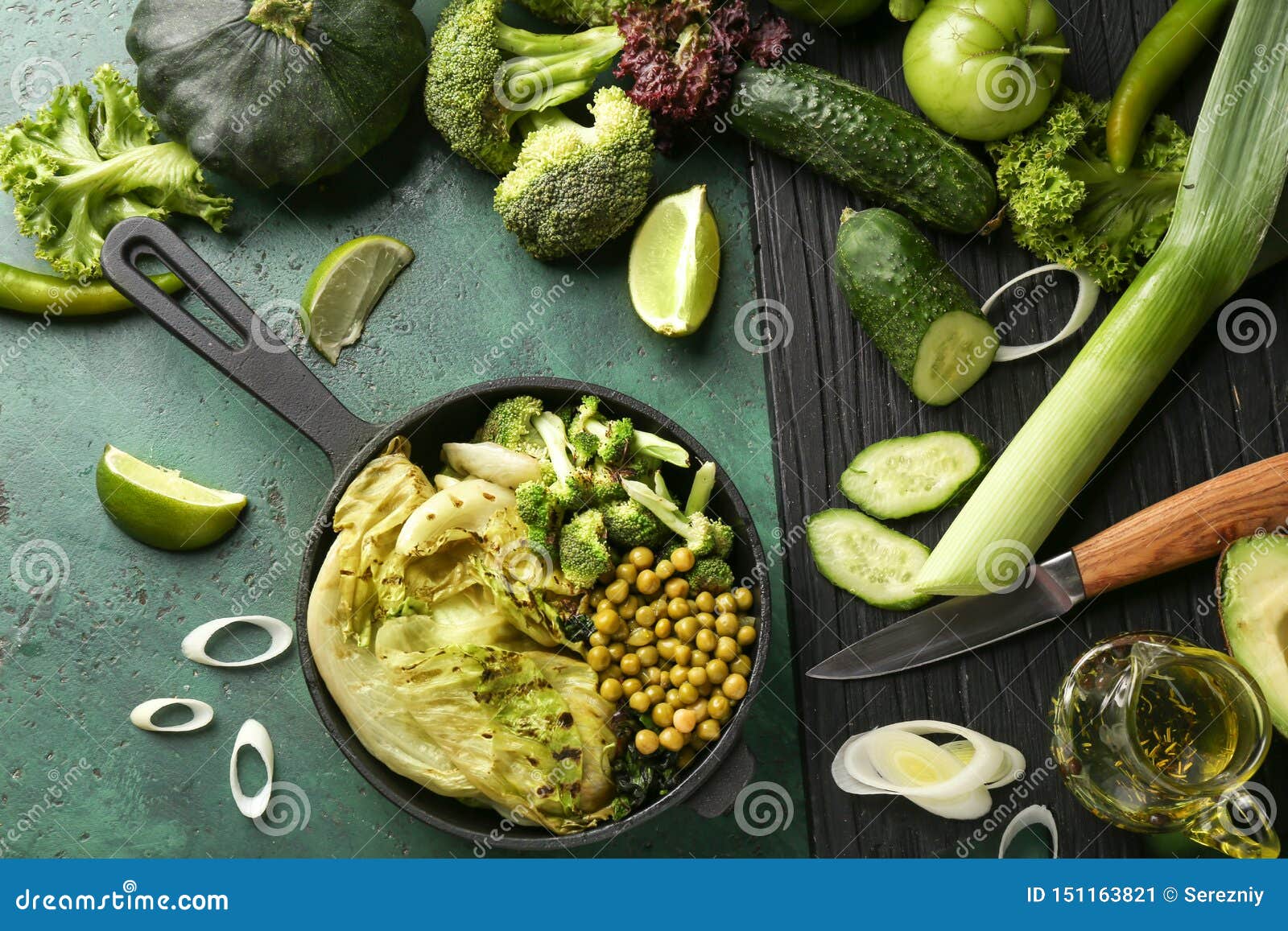 Frying Pan with Healthy Vegetable Salad and Ingredients on Color Table
