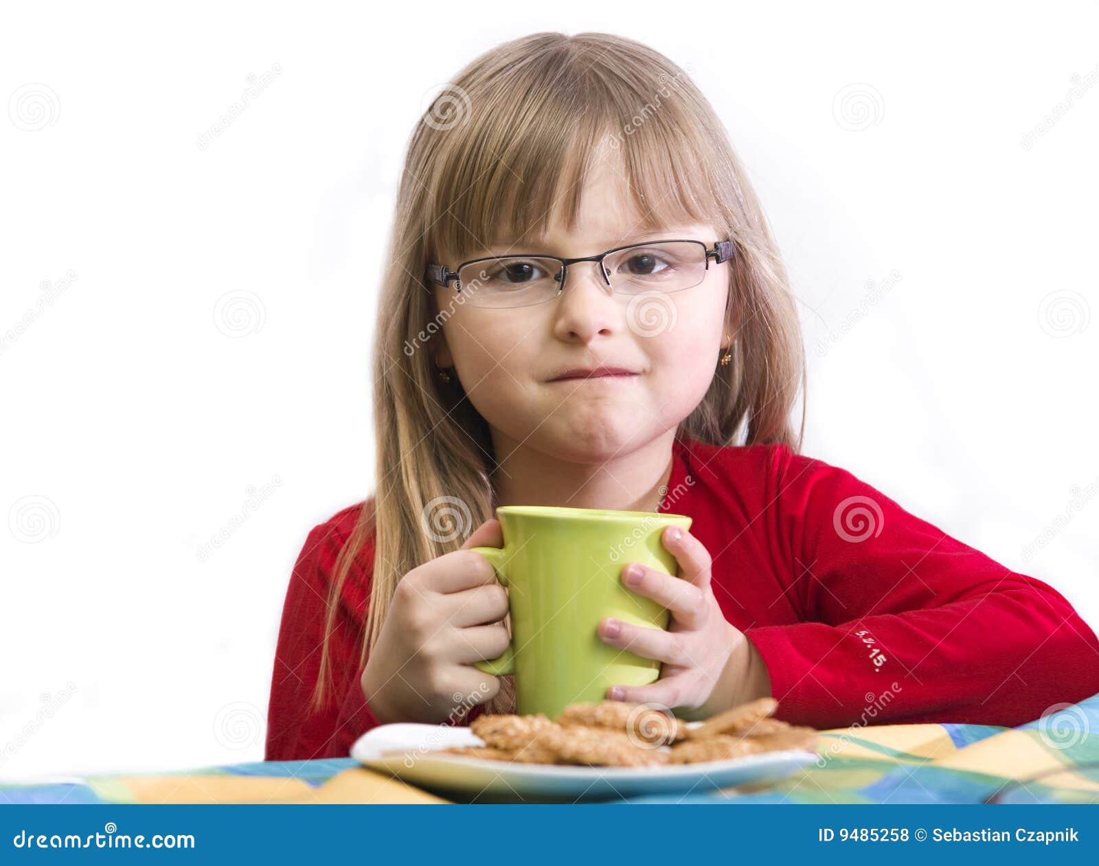 Frühstückmädchen. Portrait eines jungen Mädchens, das am Frühstückstische, weißer Hintergrund sitzt.