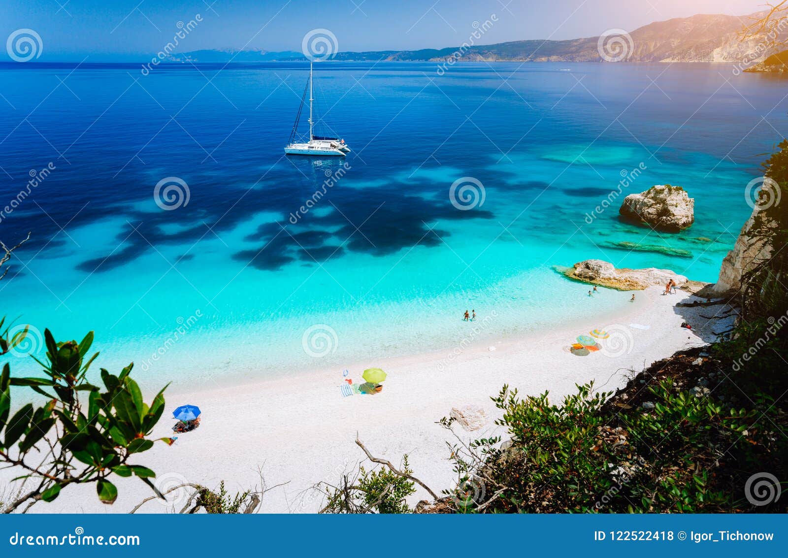 fteri beach, cephalonia kefalonia, greece. white catamaran yacht in clear blue sea water. tourists on sandy beach near