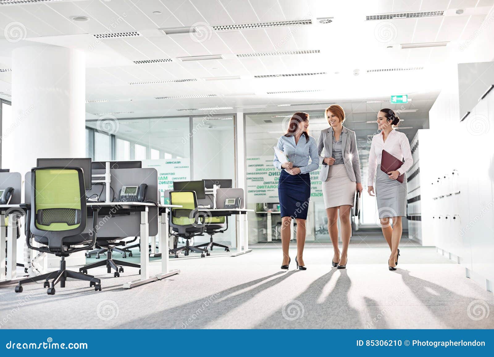 full-length of businesswomen with file folders walking in office