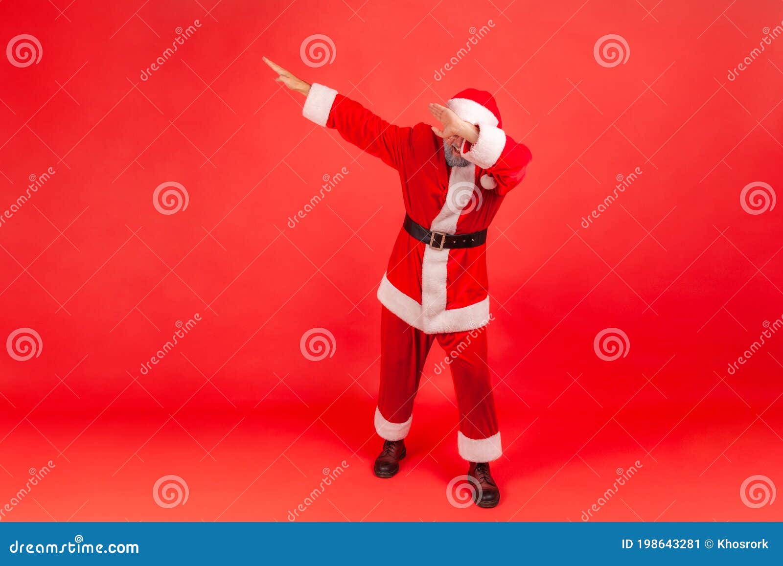 full length excited man in santa claus costume raising hands showing dab gesture, keeping youth trends dancing dubdance,