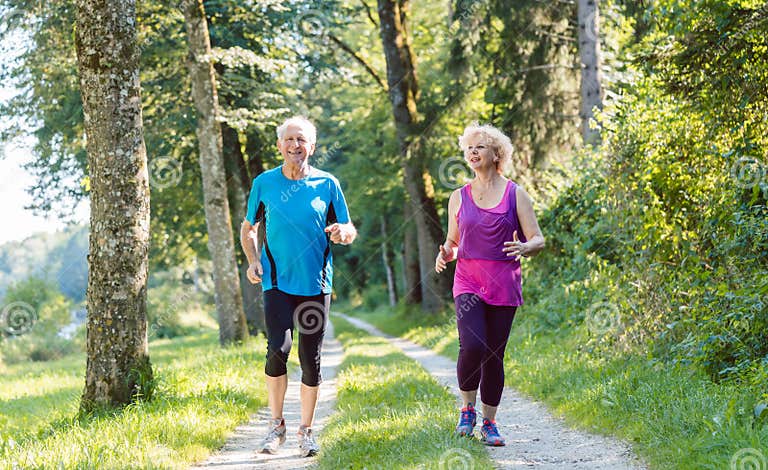 Two Active Seniors with a Healthy Lifestyle Smiling while Joggin Stock ...