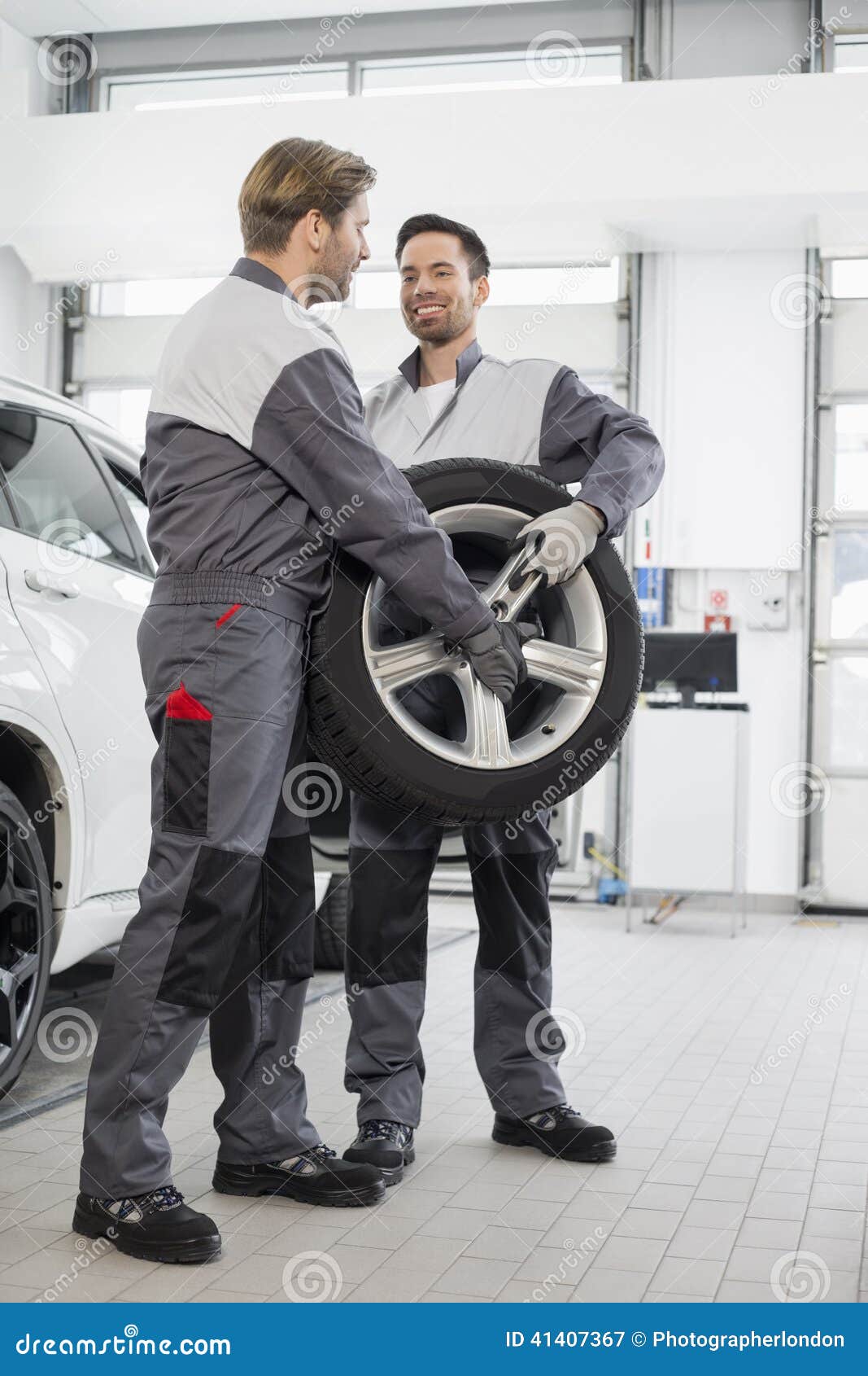 Full Length of Maintenance Engineers Carrying Tire in Car