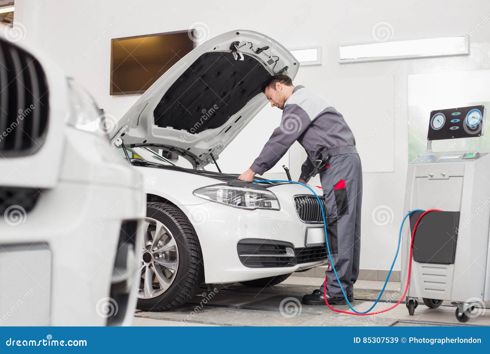 Full Length of Male Engineer Examining Car in Automobile Repair Shop