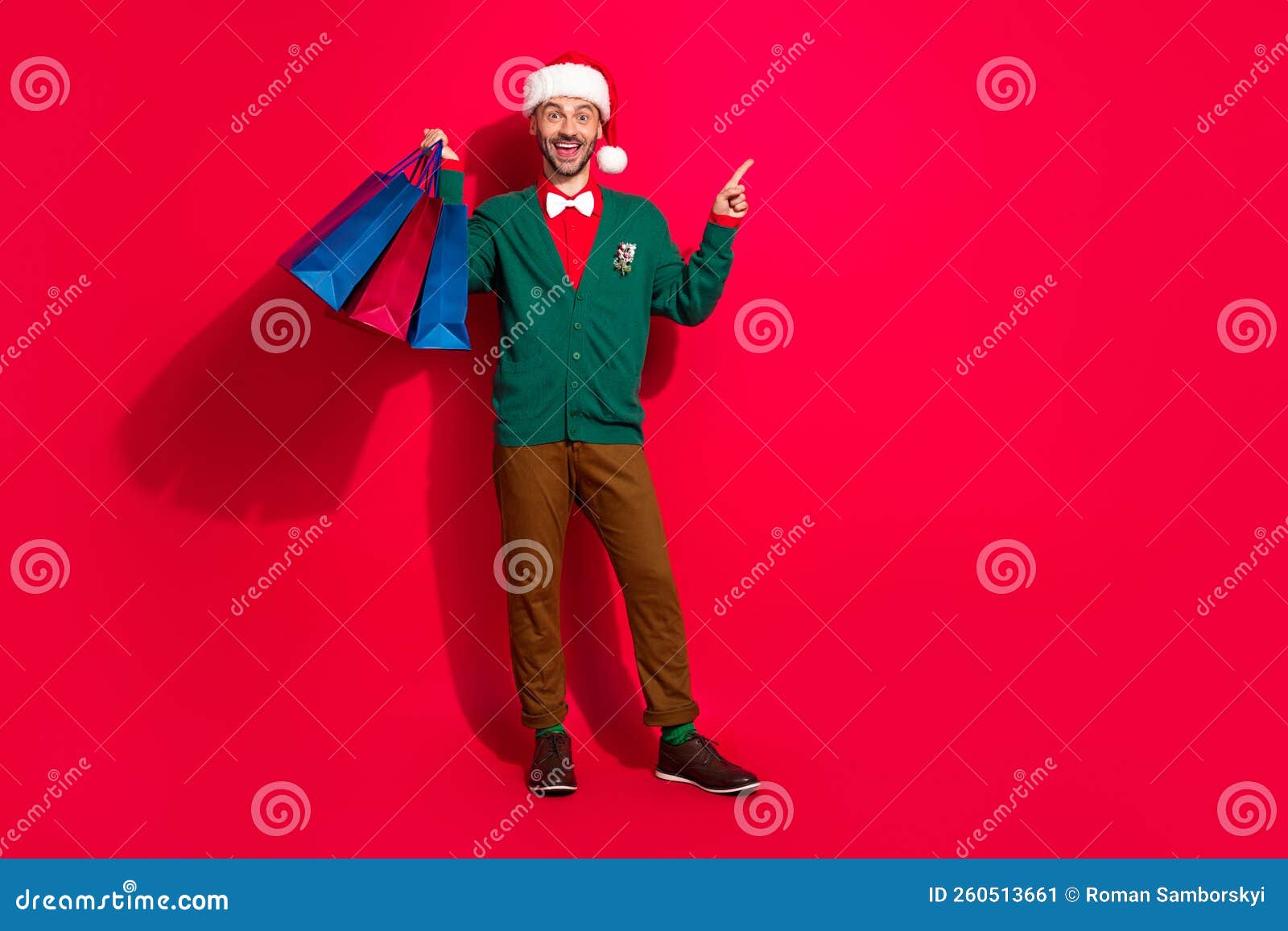 Full length photo of impressed man wear x-mas green cardigan rising noel presents bargains empty space isolated red color background.
