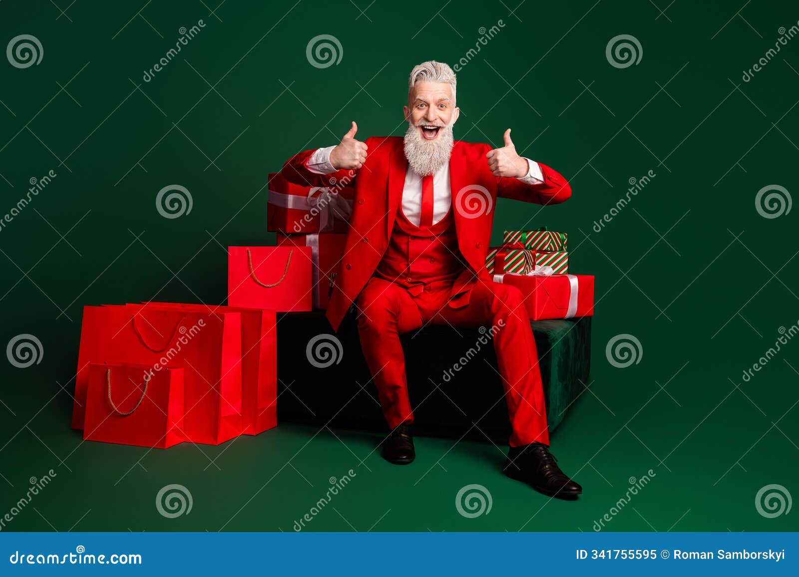 full length portrait of elegant stylish santa show thumb up giftbox shop bags red new year suit  on green color